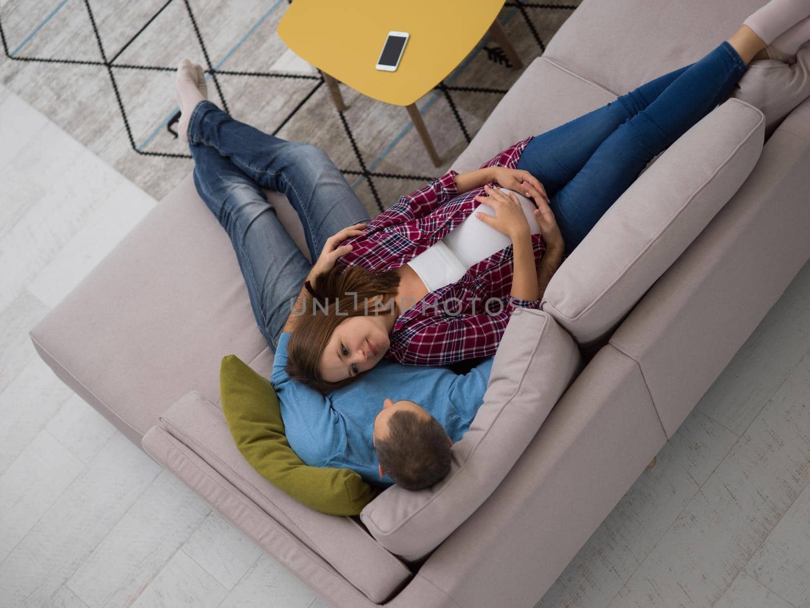 top view of happy pregnant couple relaxing on sofa couch at home