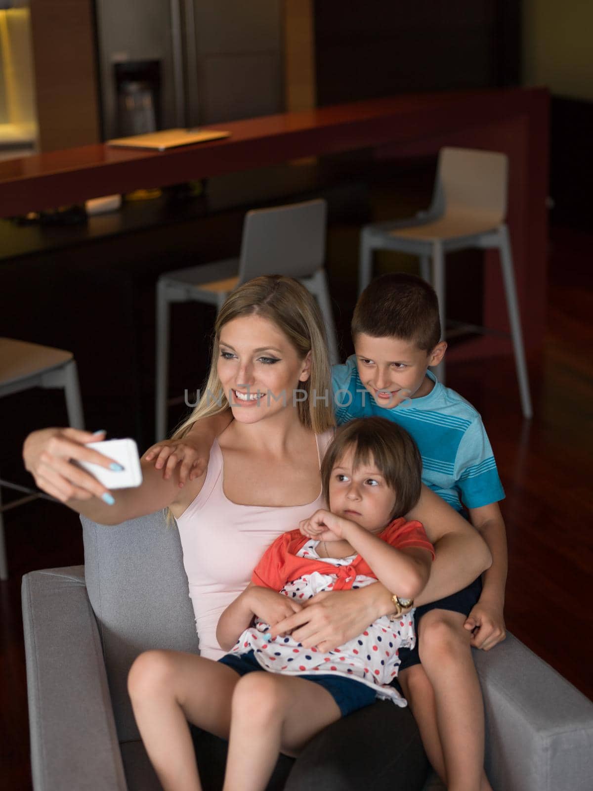 Happy family siting on sofa and using cell phone for video call  at home