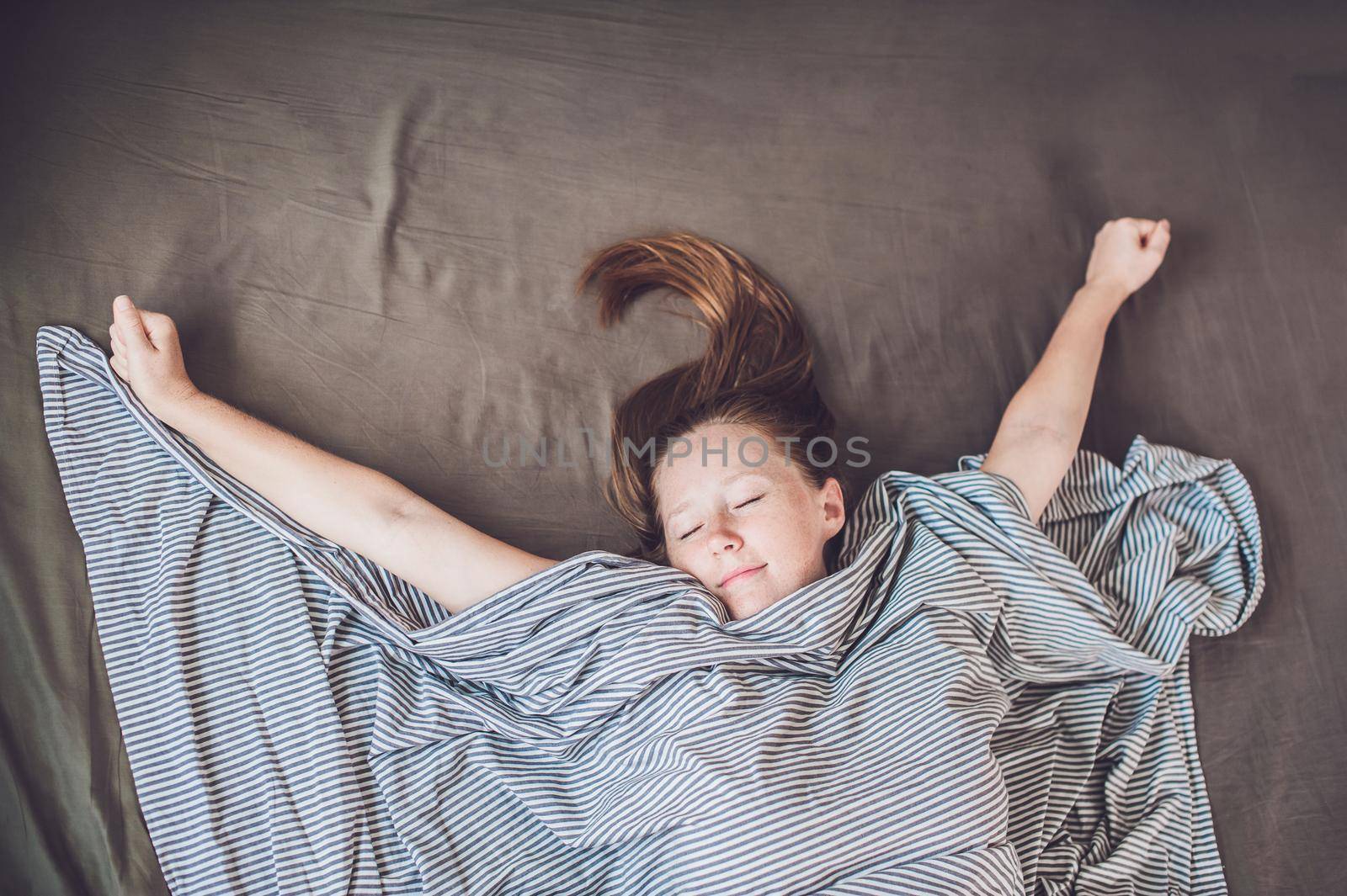 Beautiful young woman lying down in bed and sleeping, top view. Do not get enough sleep concept by galitskaya