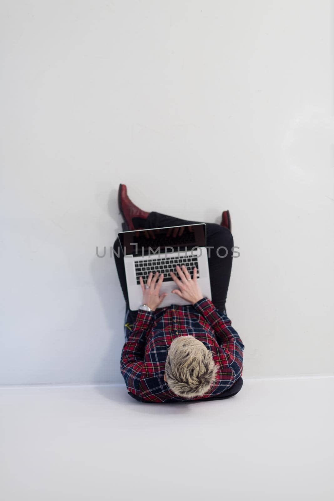 top view of young business woman working on laptop computer in modern bright startup office interior, sitting on floor