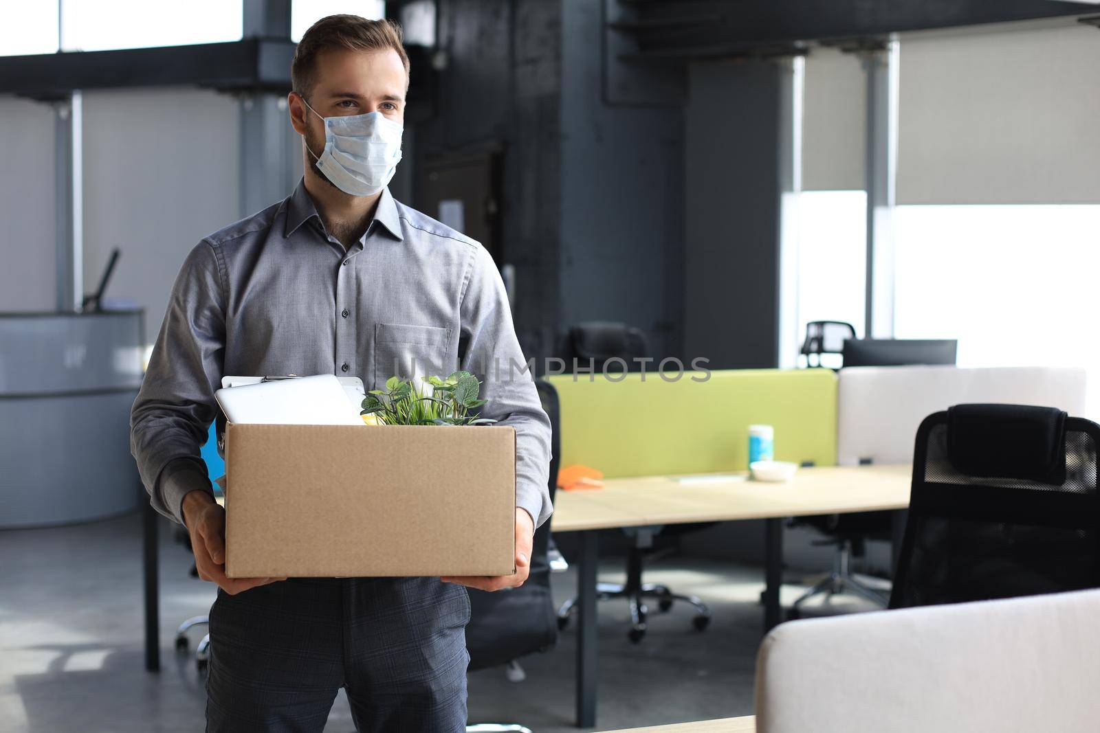 Dismissal employee in an epidemic coronavirus. Dismissed worker going from the office with his office supplies. by tsyhun