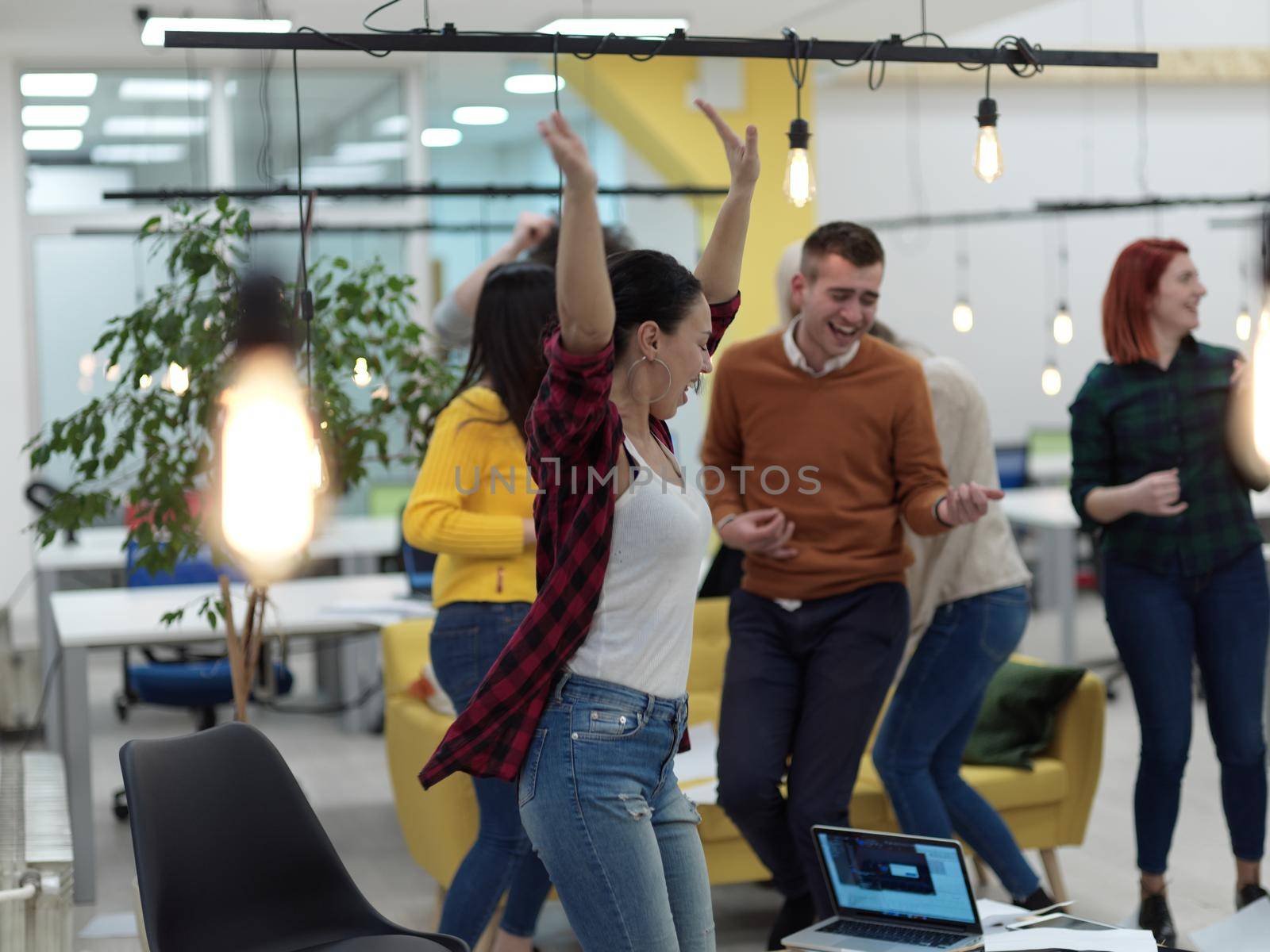 Group of business people having party and throwing paper in air at modern coworking open space startup office