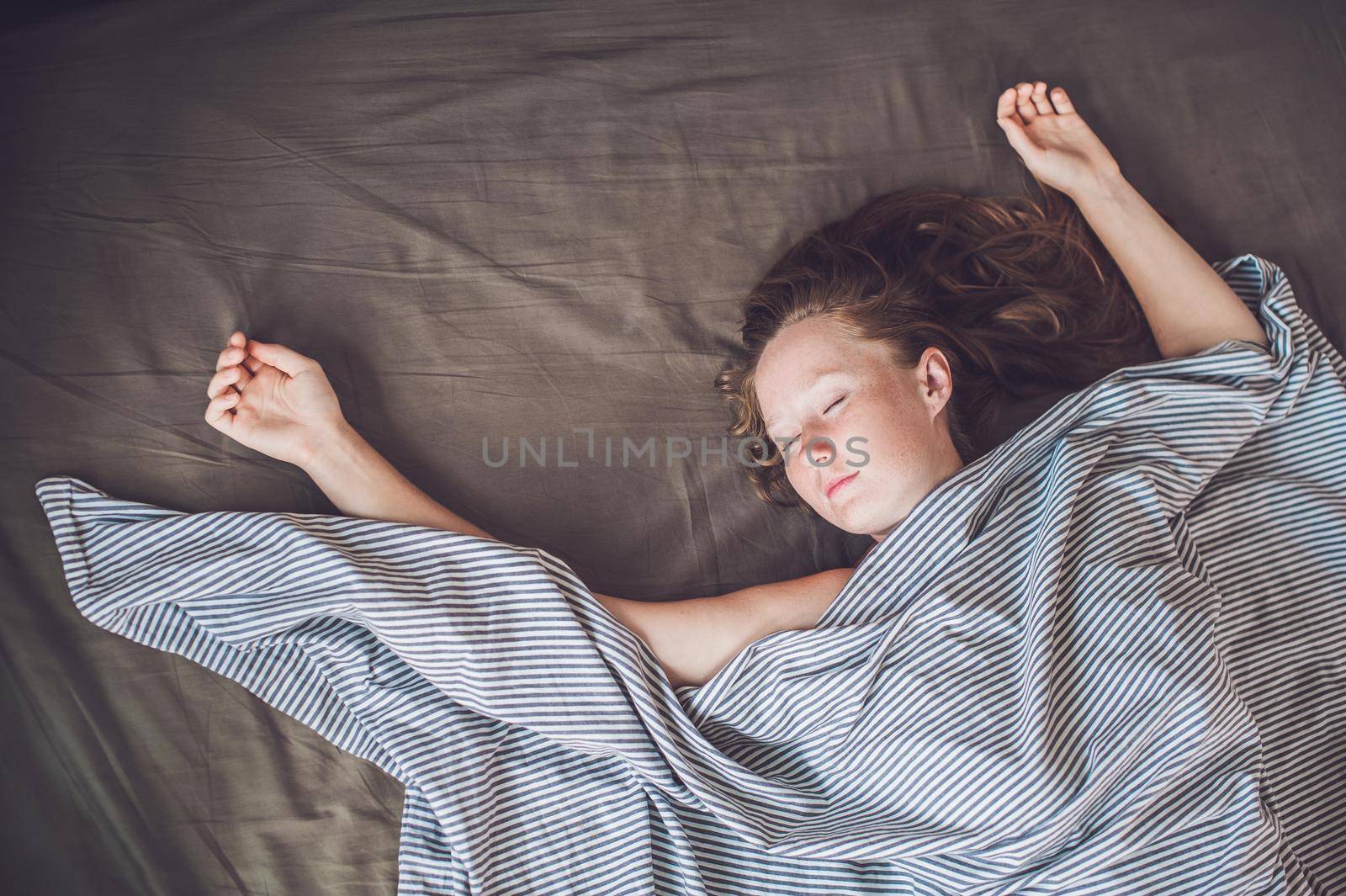 Beautiful young woman lying down in bed and sleeping, top view. Do not get enough sleep concept.