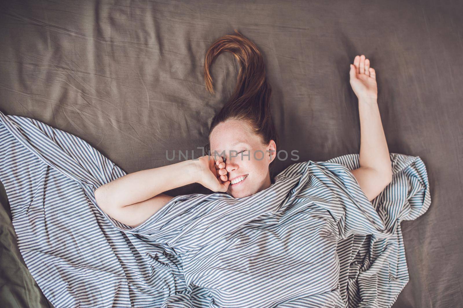 Beautiful young woman lying down in bed and sleeping, top view. Do not get enough sleep concept.