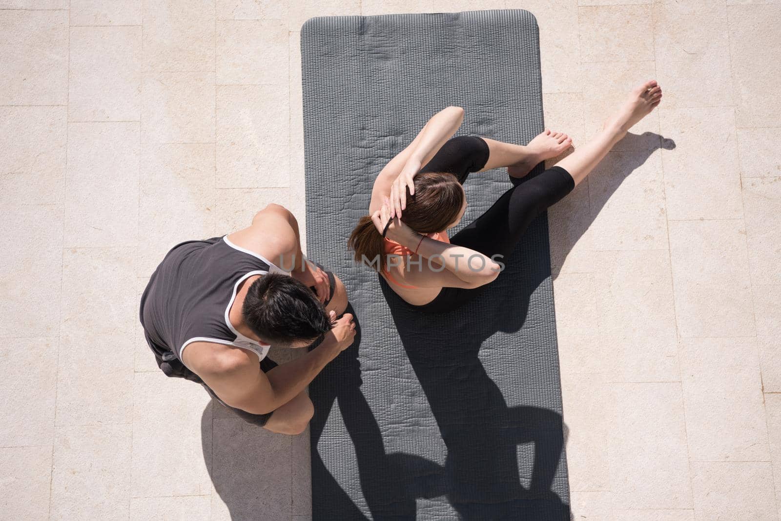 young handsome woman with personal trainer doing morning yoga exercises in front of her luxury home villa top view