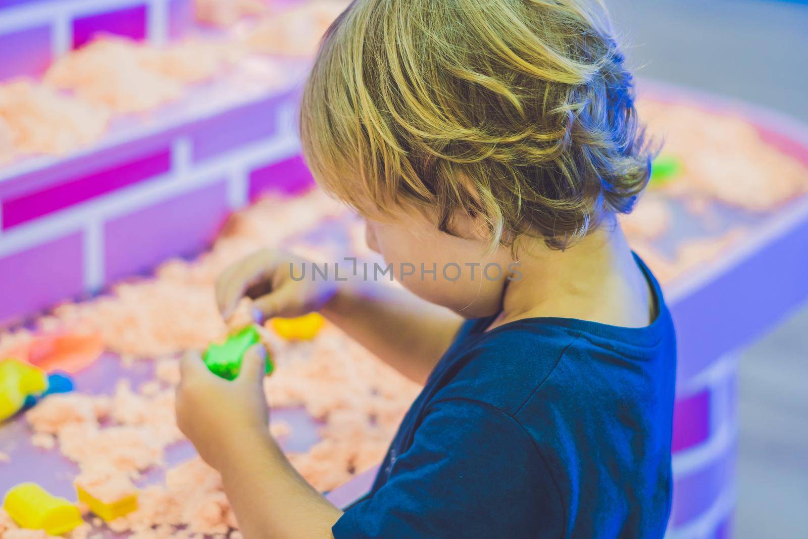Boy playing with kinetic sand in preschool. The development of fine motor concept. Creativity Game concept by galitskaya