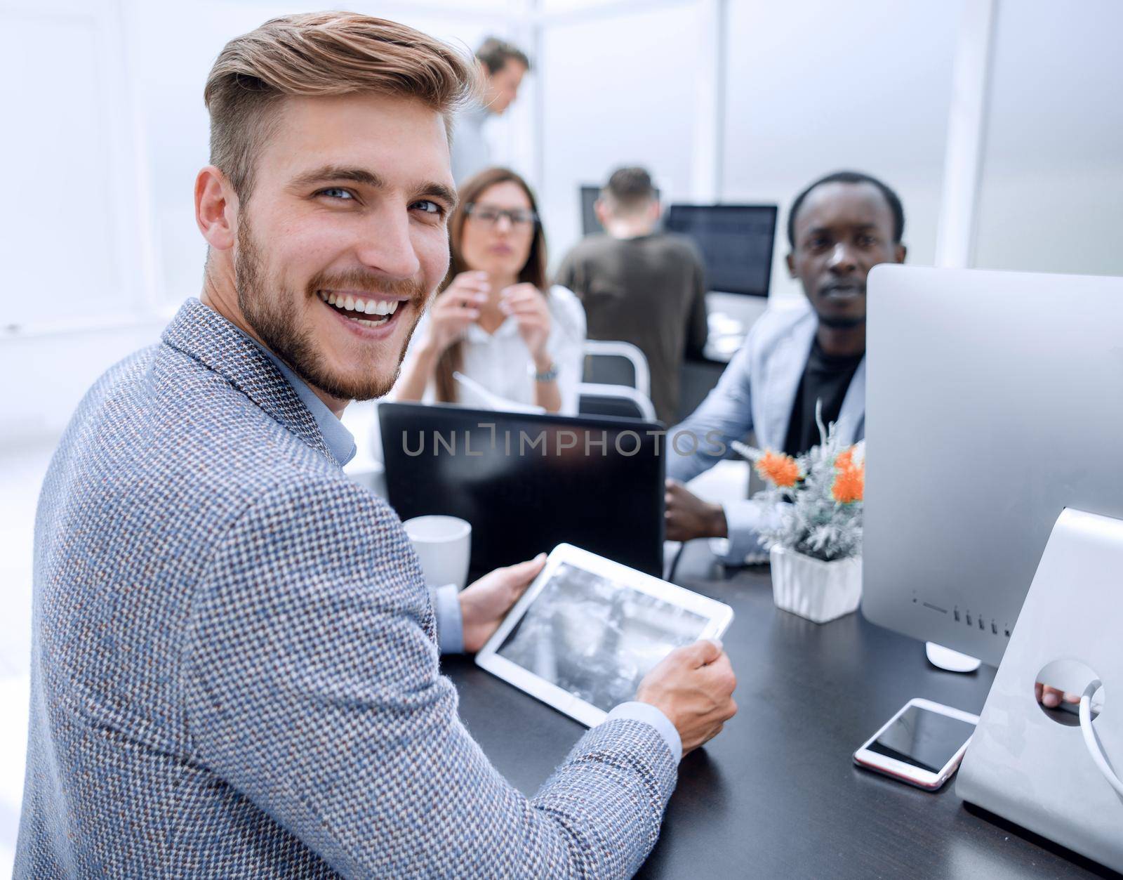 smiling businessman sitting at the office Desk by asdf