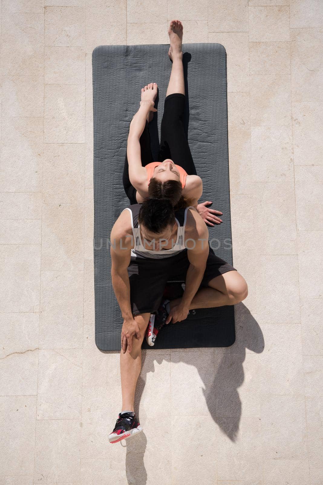 young handsome woman with personal trainer doing morning yoga exercises in front of her luxury home villa top view