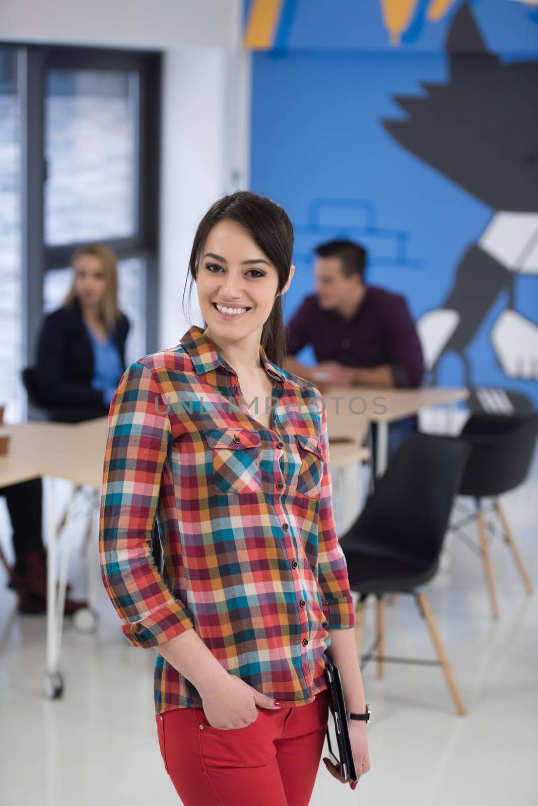 portrait of young business woman at modern startup office interior, team in meeting in background