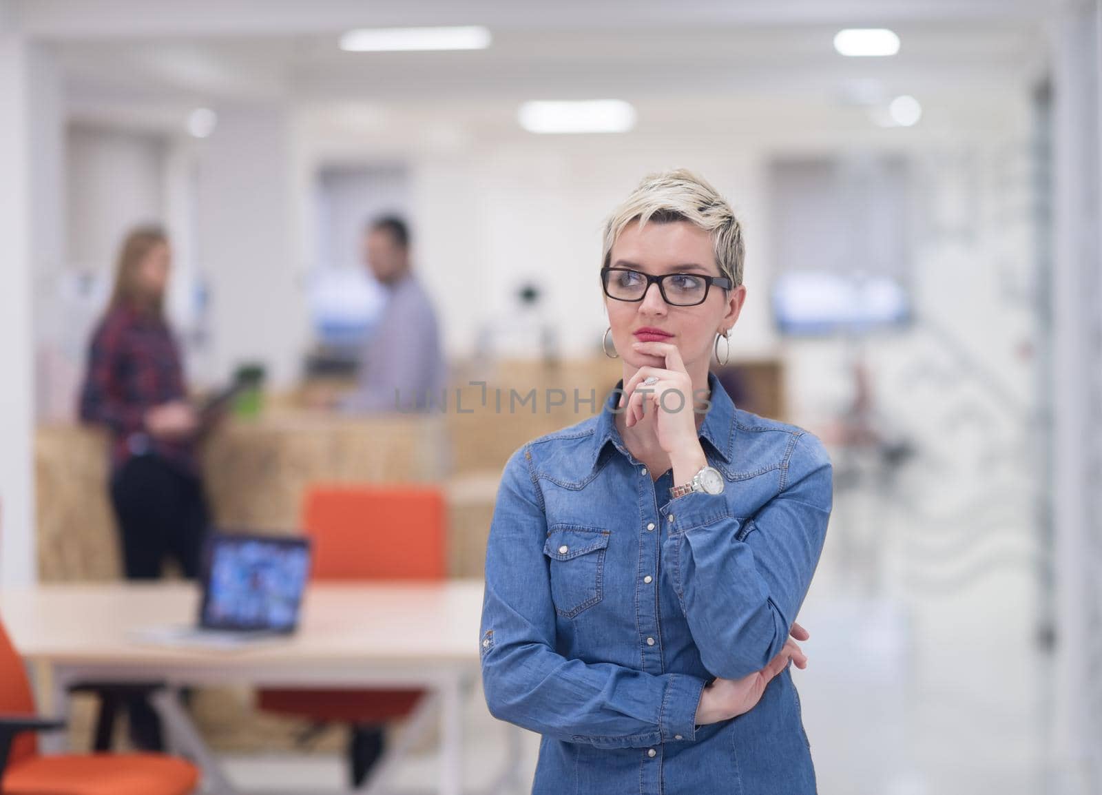 portrait of young business woman at modern startup office interior, team in meeting in background