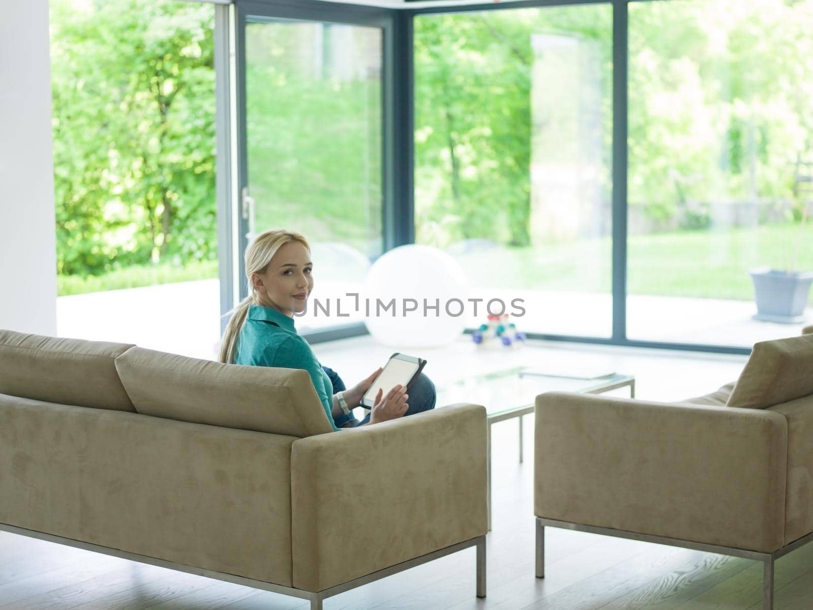 woman on sofa using tablet computer by dotshock