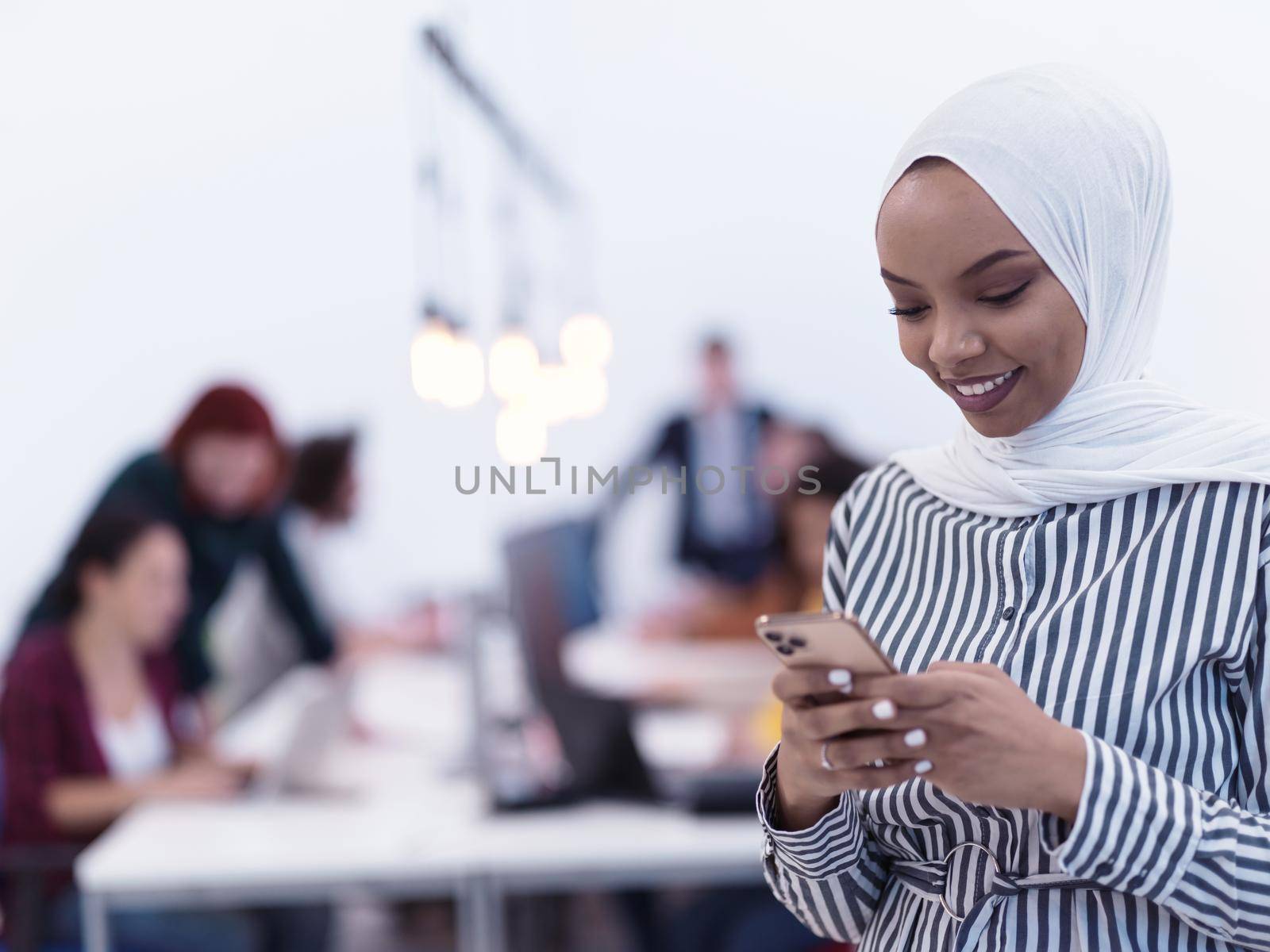 african muslim businesswoman using smart phone  wearing hijab at creative modern startup coworking open space office