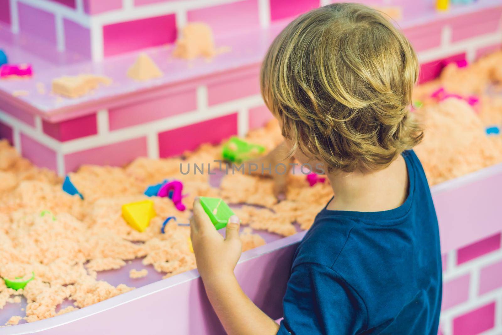 Boy playing with kinetic sand in preschool. The development of fine motor concept. Creativity Game concept.