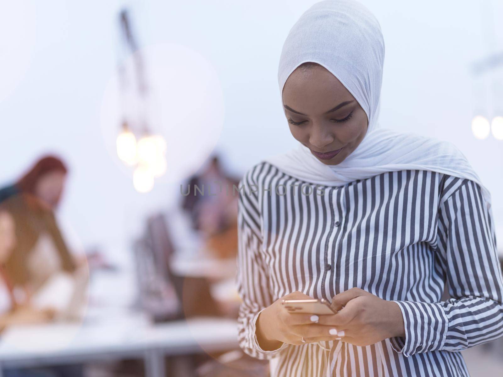 african muslim businesswoman using smart phone  wearing hijab at creative modern startup coworking open space office