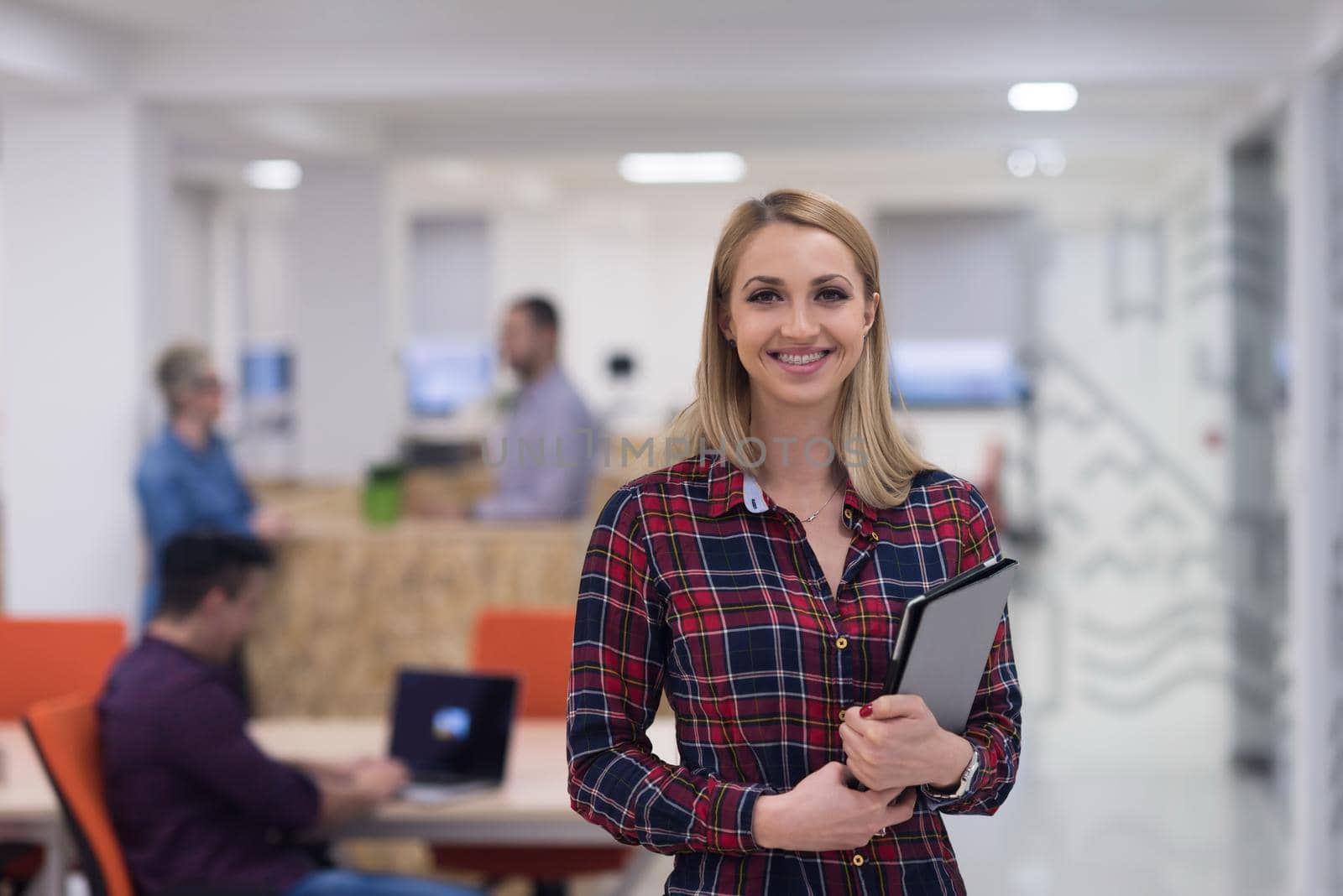 portrait of young business woman at modern startup office interior, team in meeting in background