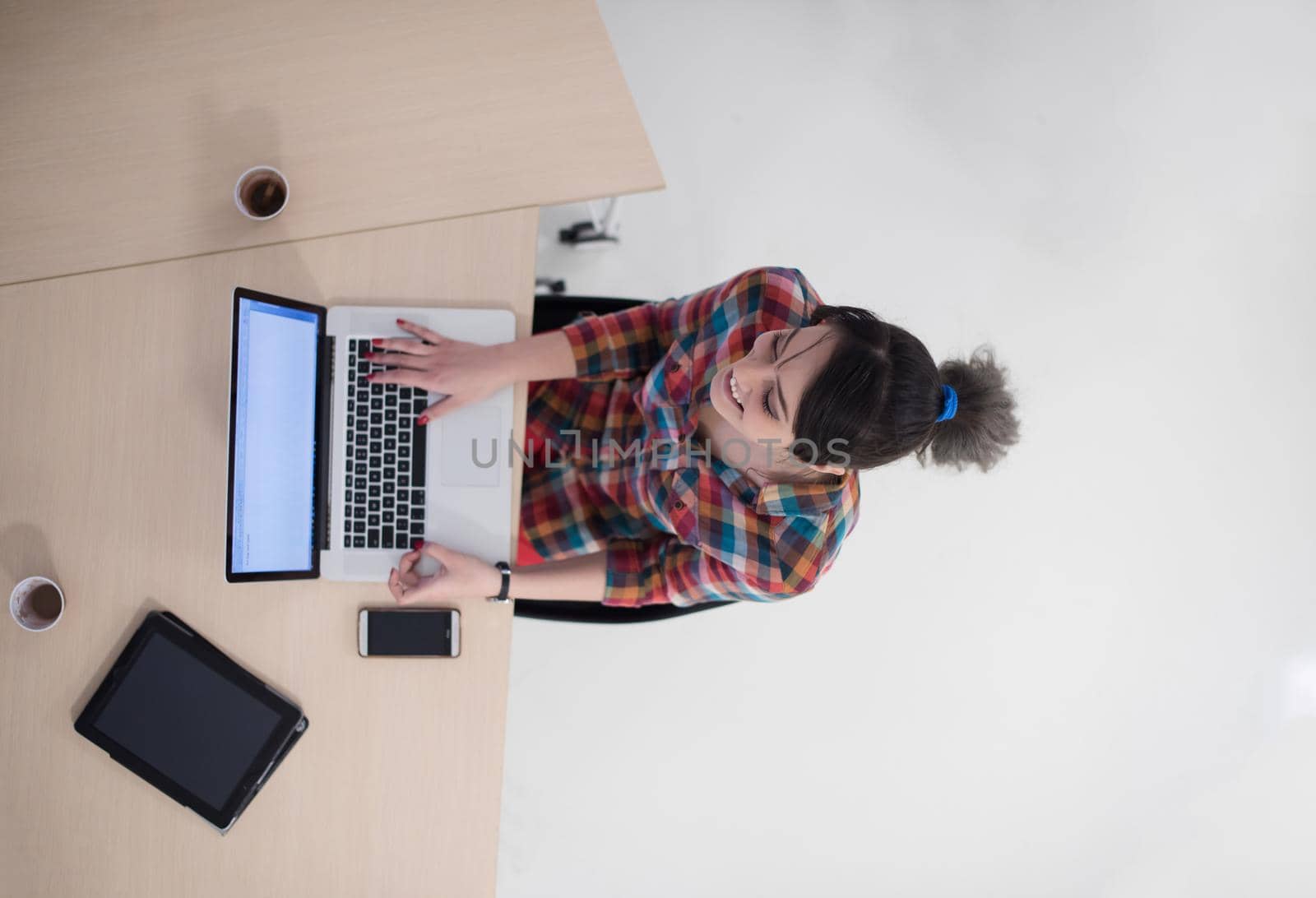 top view of young business woman working on laptop computer in modern bright startup office interior