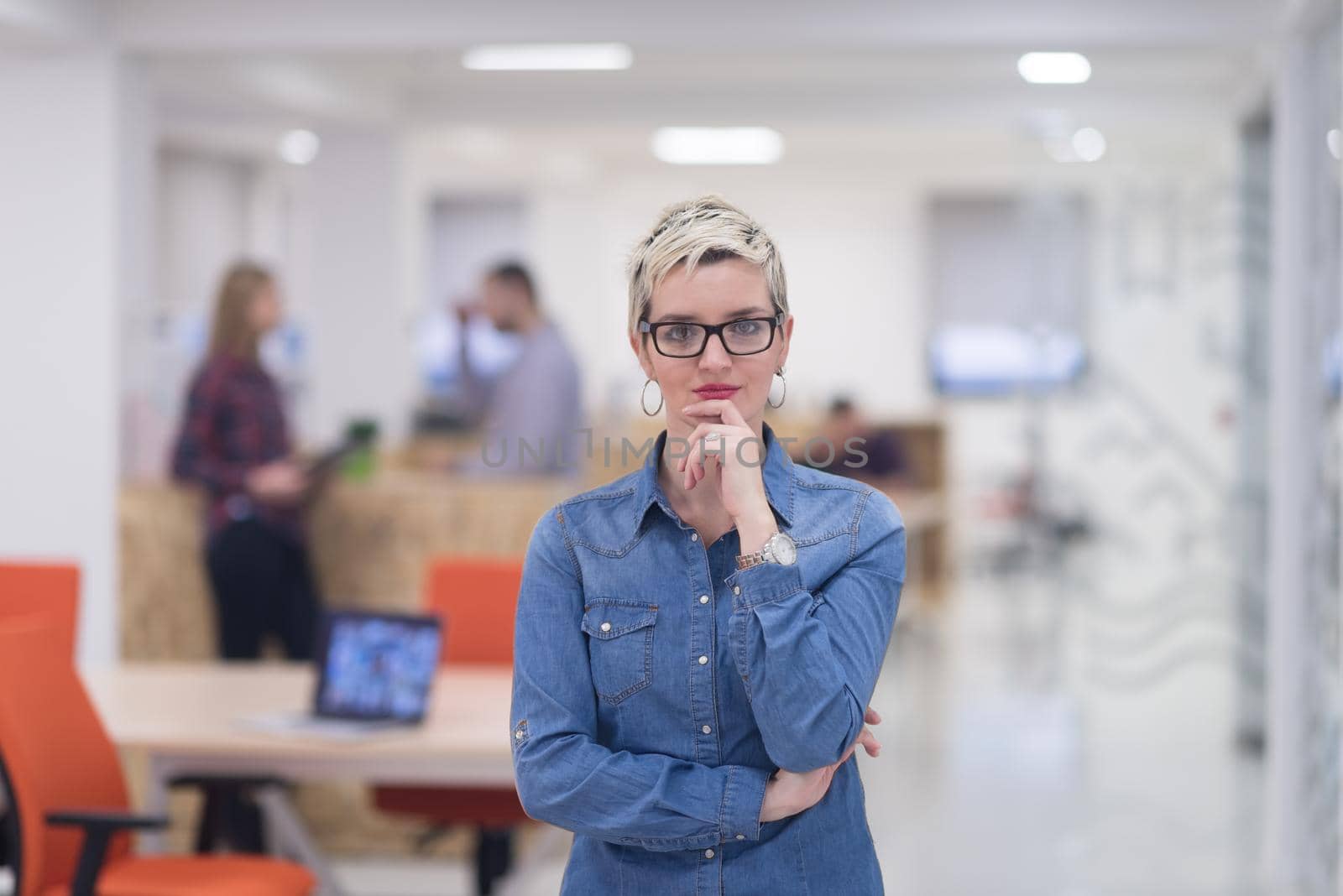 portrait of young business woman at modern startup office interior, team in meeting in background