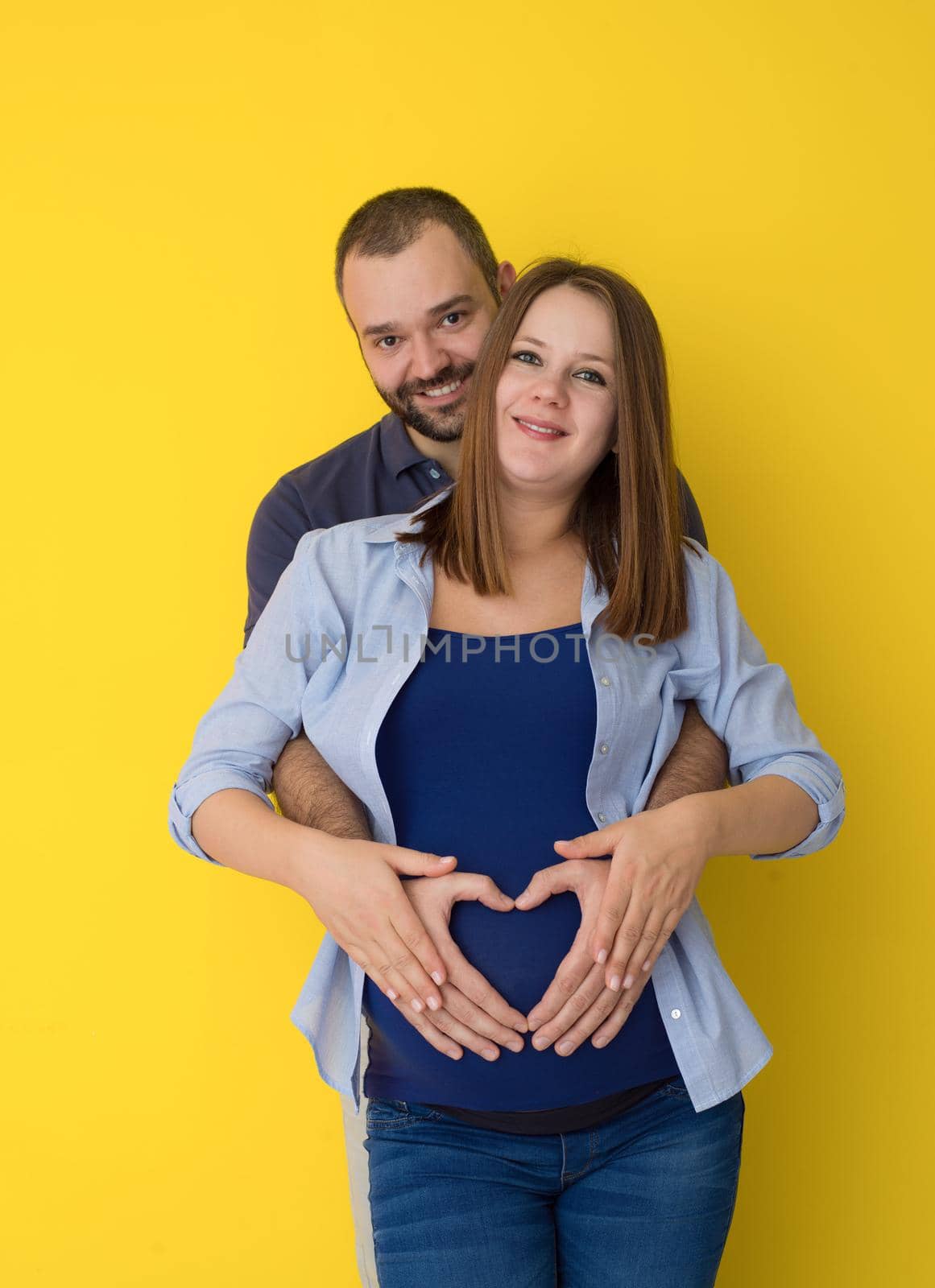 pregnant couple  isolated over yellow background by dotshock