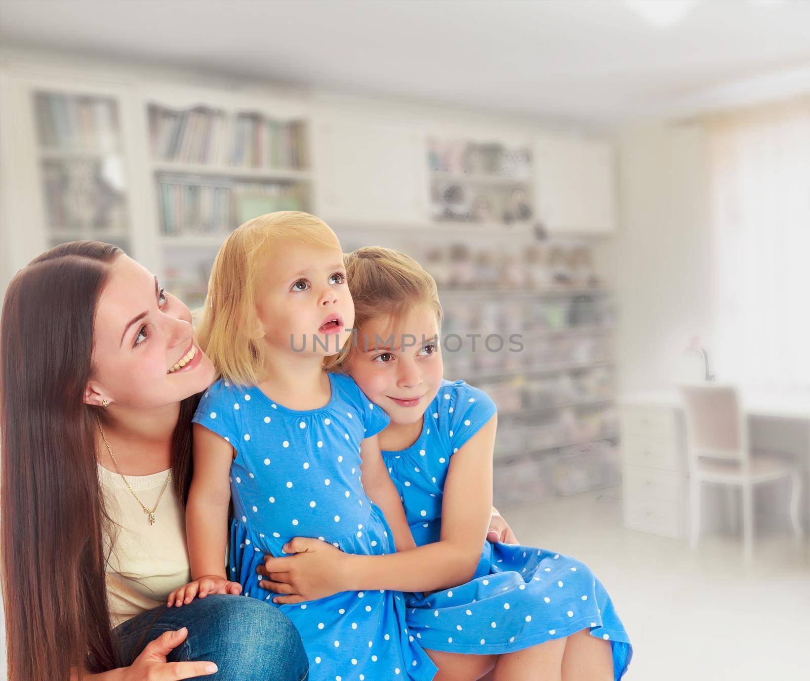 The concept of family happiness and mutual understanding between parents and children.Beautiful young mother with her two daughters. All look up.