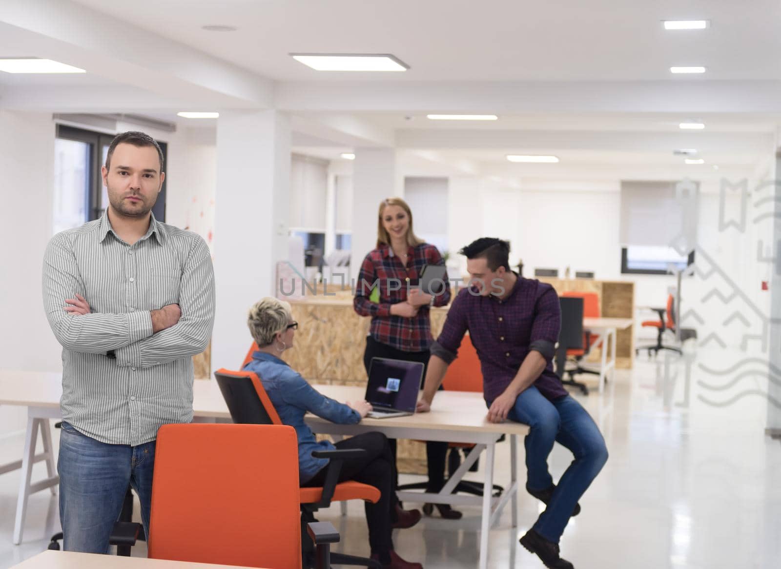 portrait of young businessman in casual clothes at modern  startup business office space,  team of people working together in background