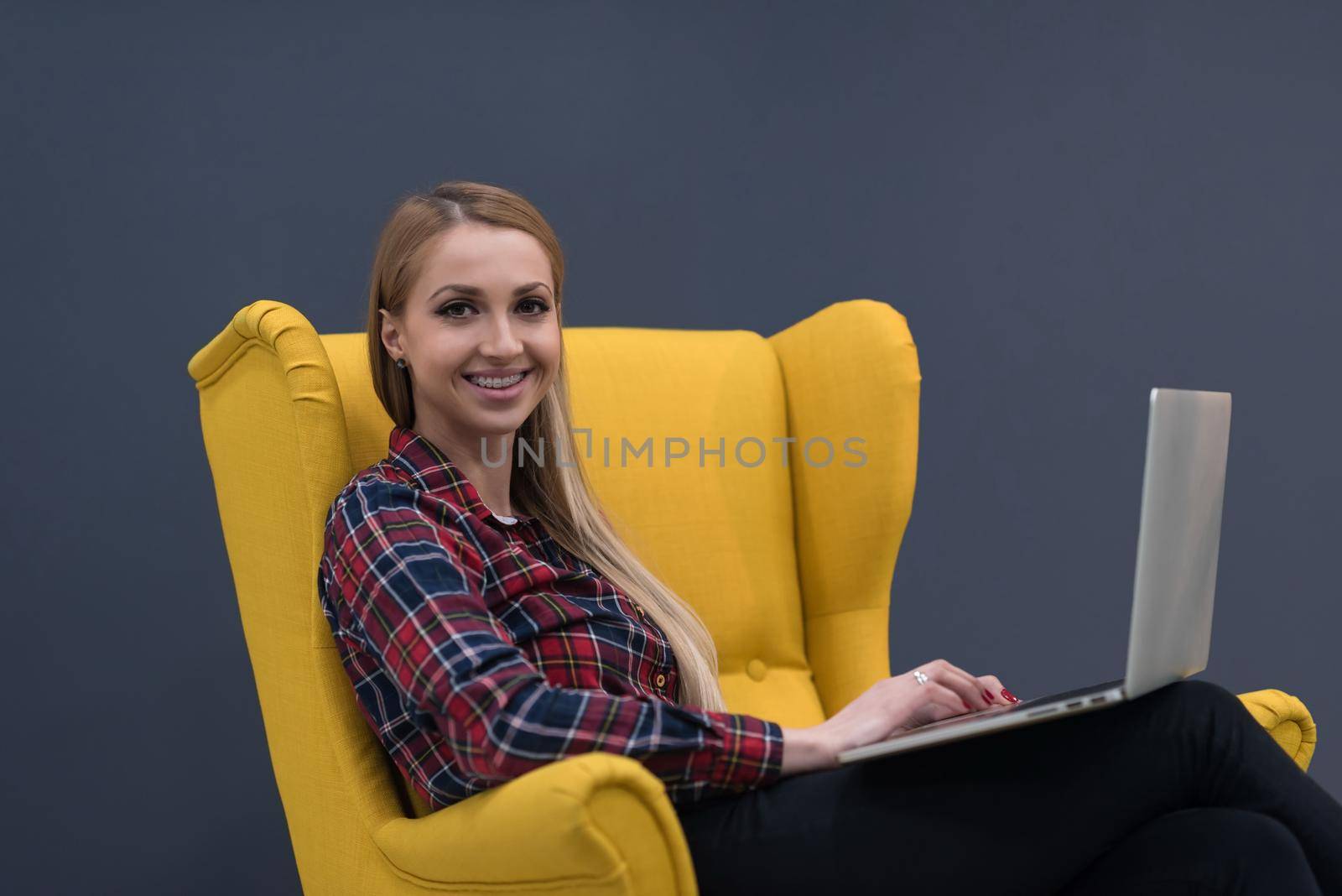 startup business, woman  working on laptop and sitting on yellow armchair by dotshock