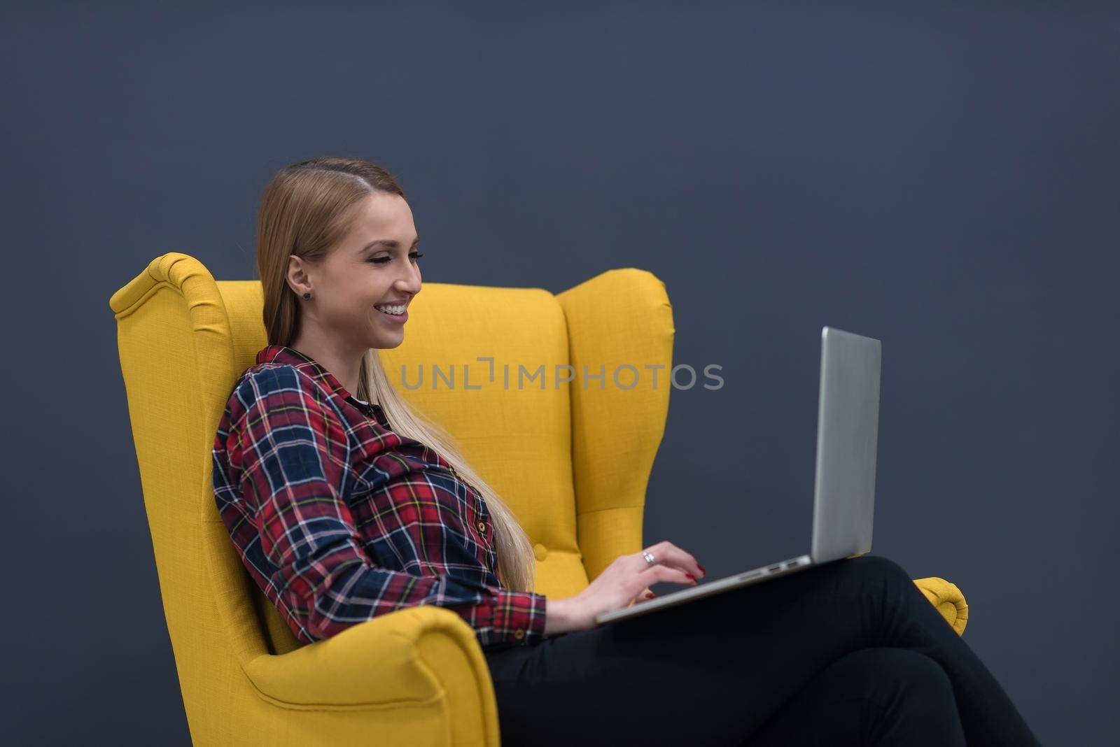 startup business, woman  working on laptop computer at modern office and sitting on creative yellow armchair