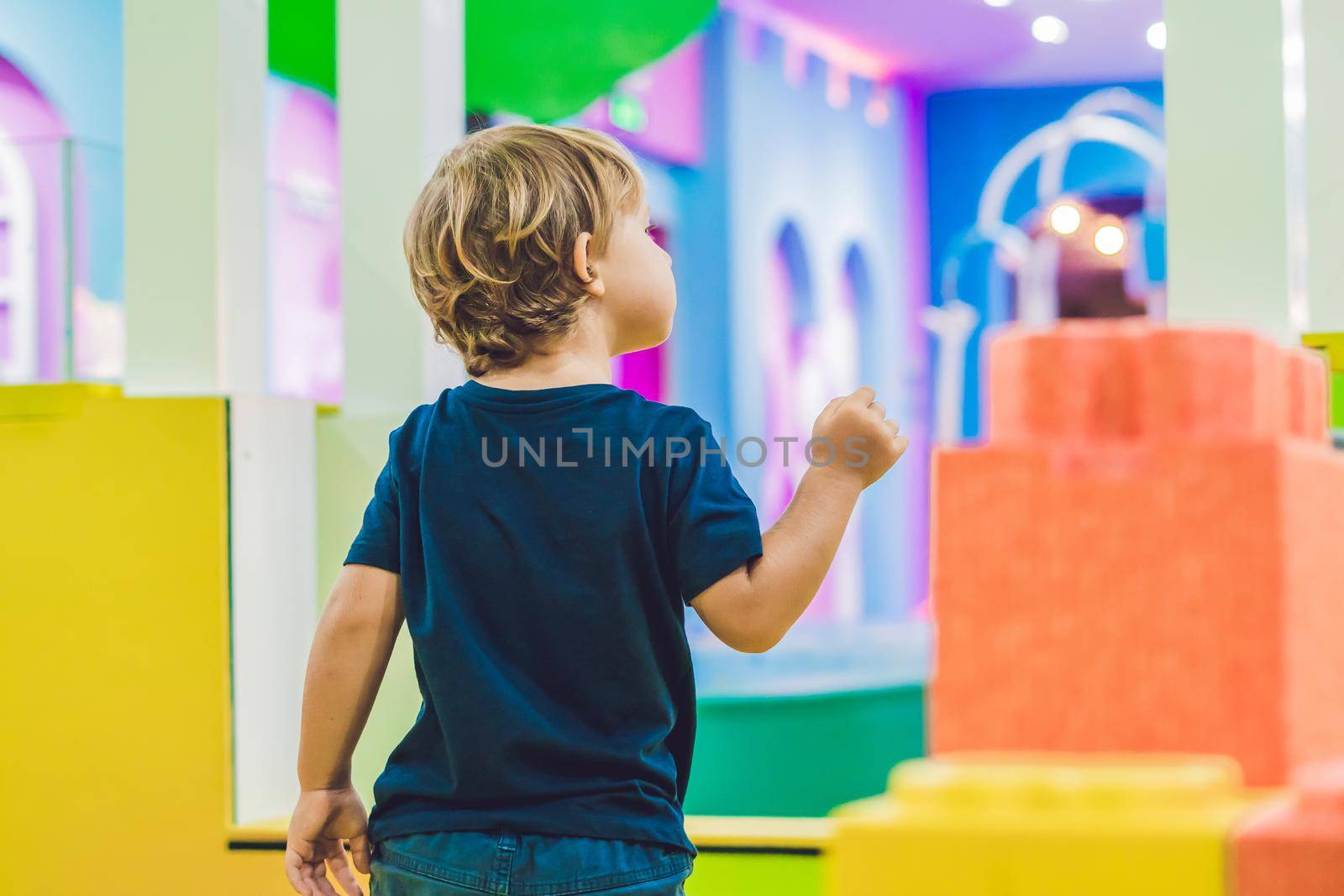 Happy boy playing indoors with big plastic construction blocks.