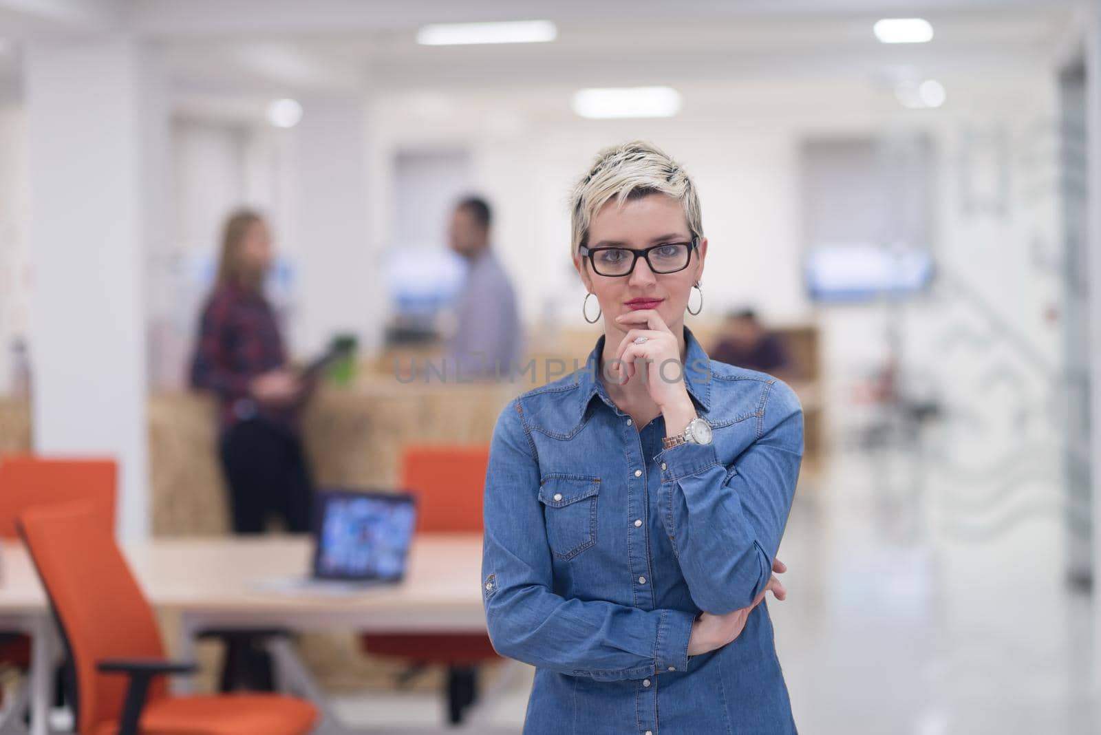 portrait of young business woman at modern startup office interior, team in meeting in background