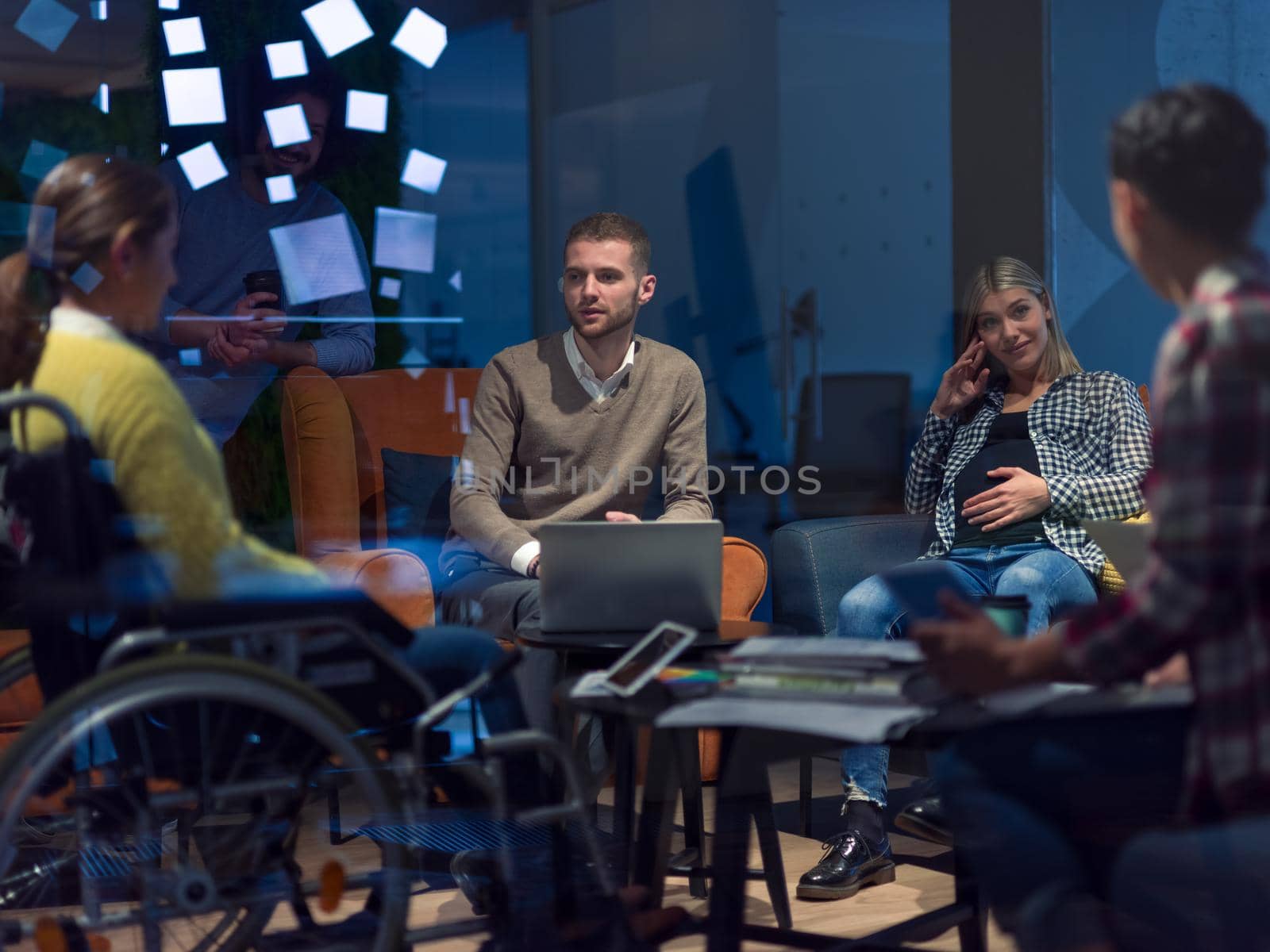 Disabled businesswoman in a wheelchair having a meeting with the diverse business people team at modern startup open space office 