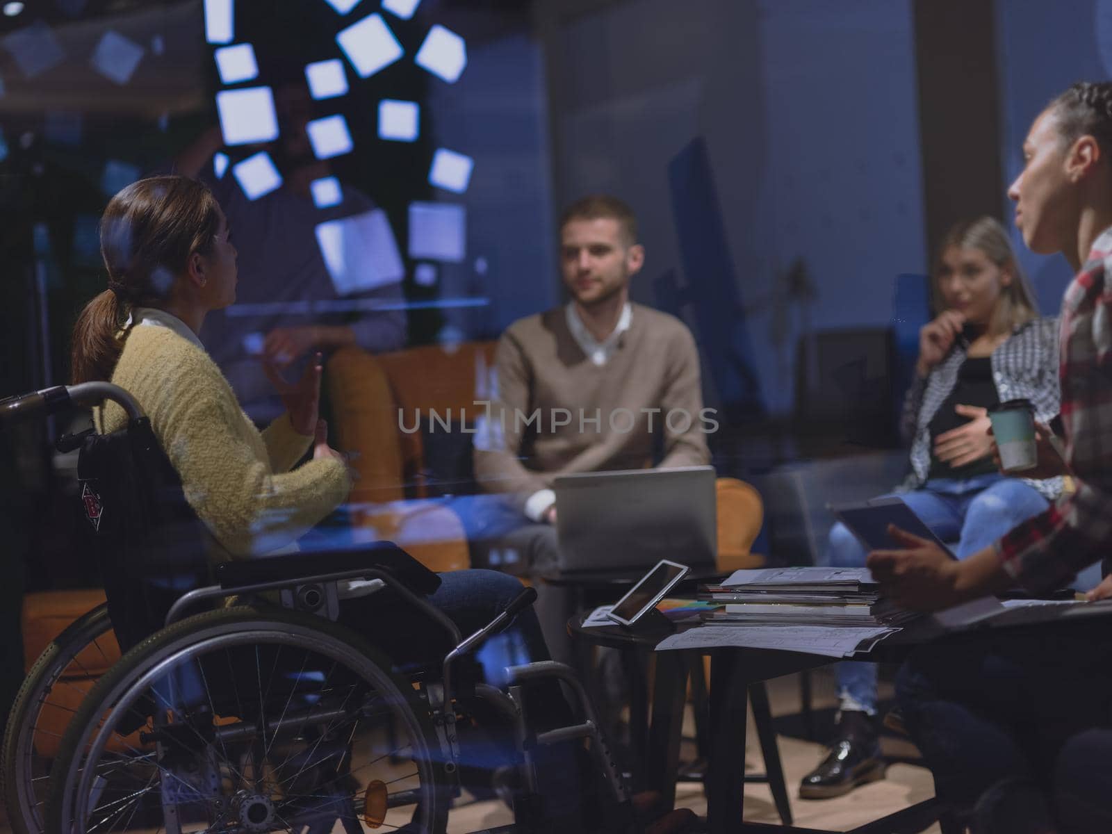 Businesswoman in wheelchair having business meeting with team at modern office  by dotshock