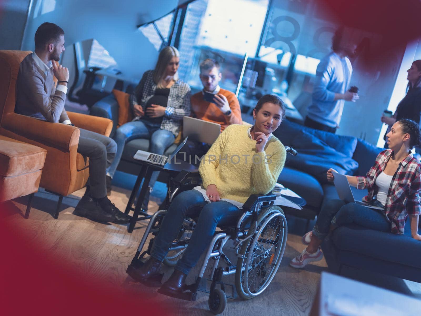 Portrait of disabled businesswoman in a wheelchair in front of her diverse business team at office by dotshock