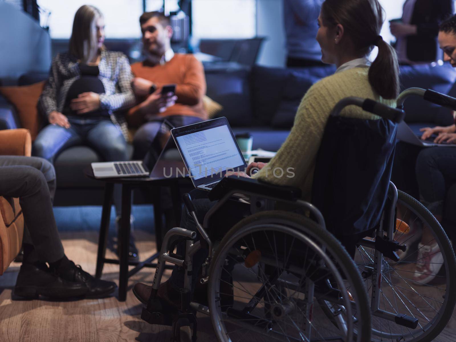 Young woman in wheelchair working on laptop at office. Getting an education at home concept by dotshock