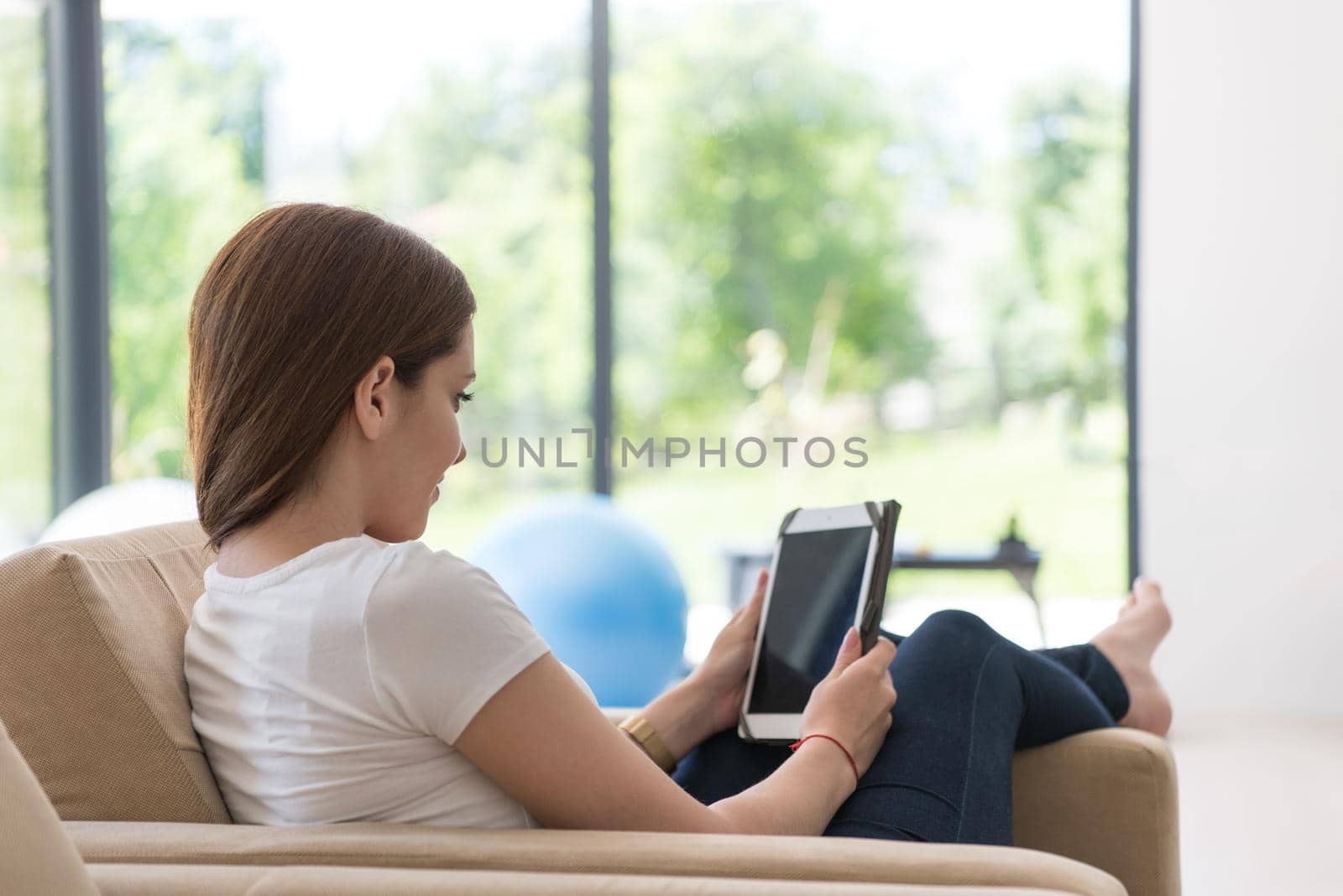 woman sitting on sofa with tablet computer by dotshock