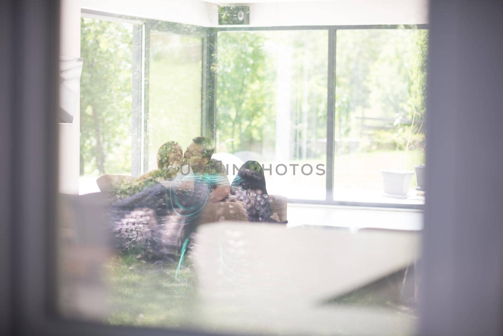 Young couple relaxing at luxurious home with tablet and laptop computers reading in the living room on the sofa couch.