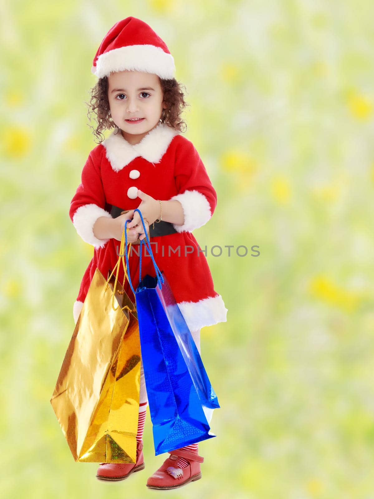 Little girl in costume of Santa Claus with colorful packages by kolesnikov_studio