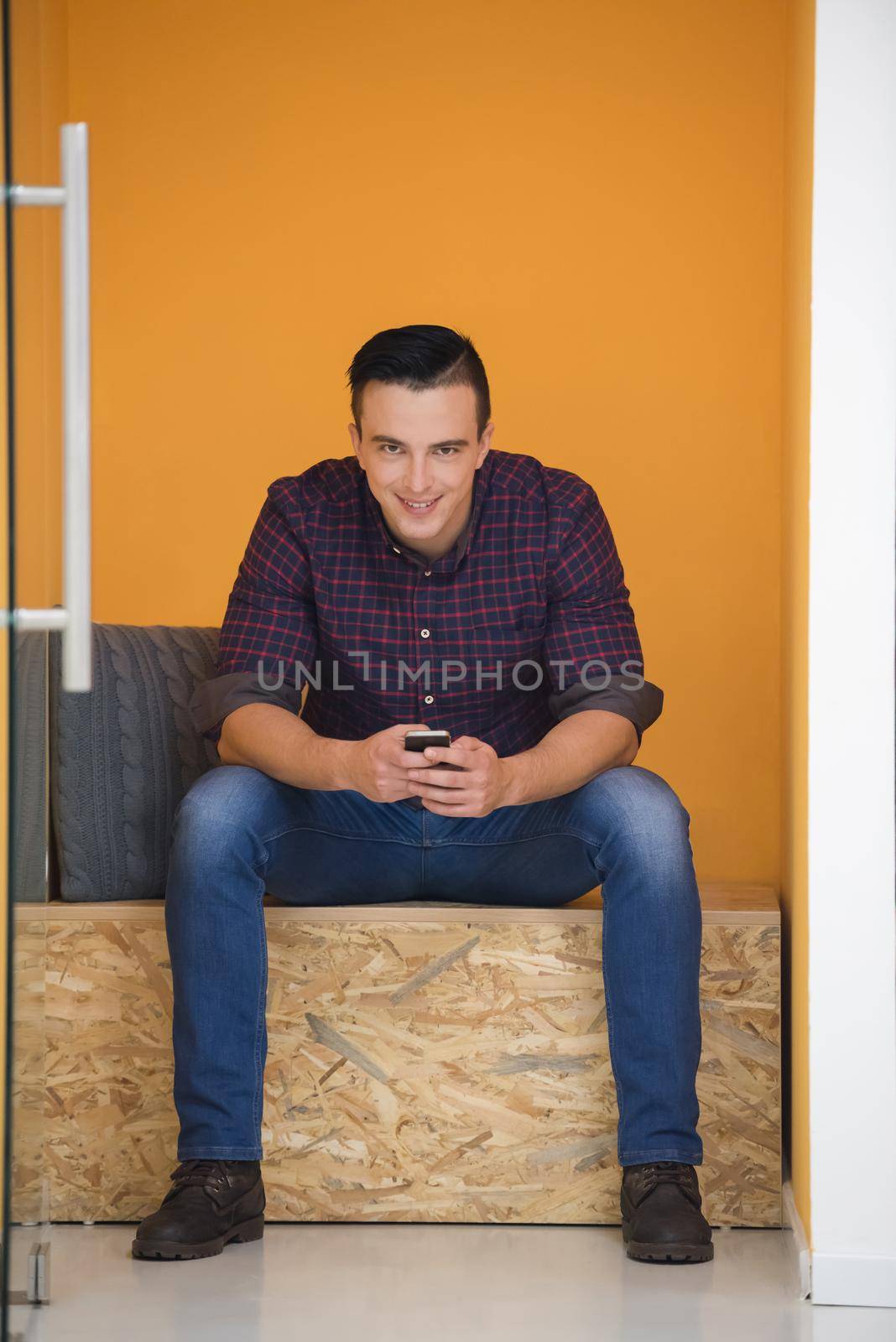 young man in crative box working on smart phone, startup business modern office room  interior