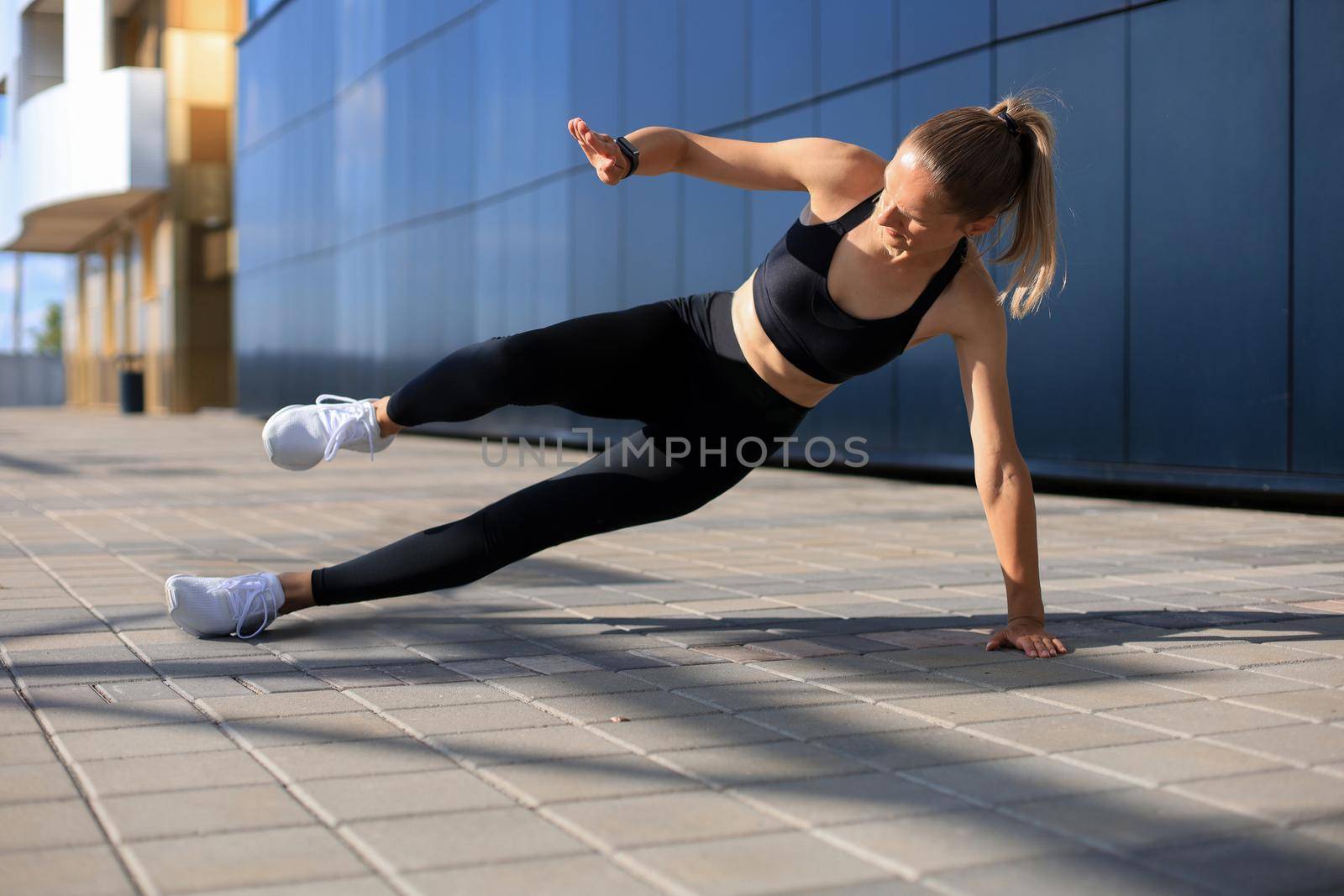 Fitness woman in sportswear doing side plank exercise outdoors
