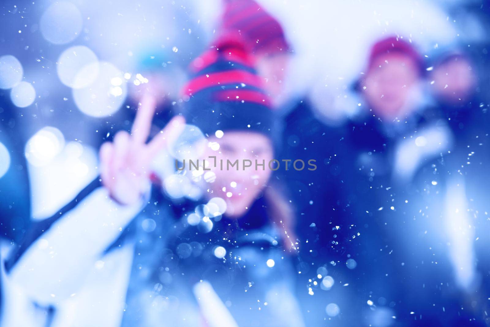 Abstract blurred photo of young happy woman with her business team enjoying snowy winter day while snowflakes flying around them during a team building in the mountain forest