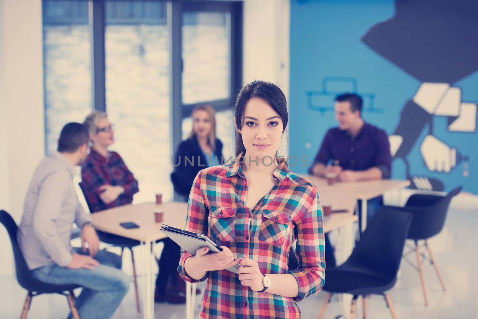 portrait of young business woman at modern startup office interior, team in meeting in background