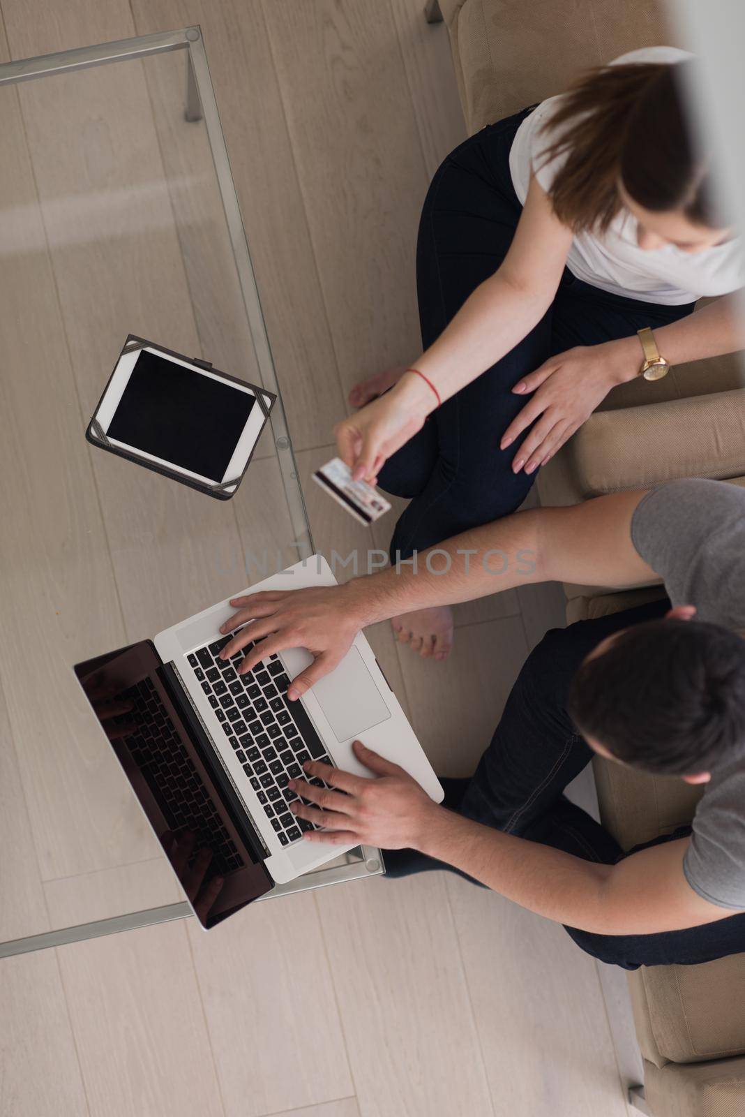 happy young couple buying online using laptop a computer and a credit card in their luxury home villa