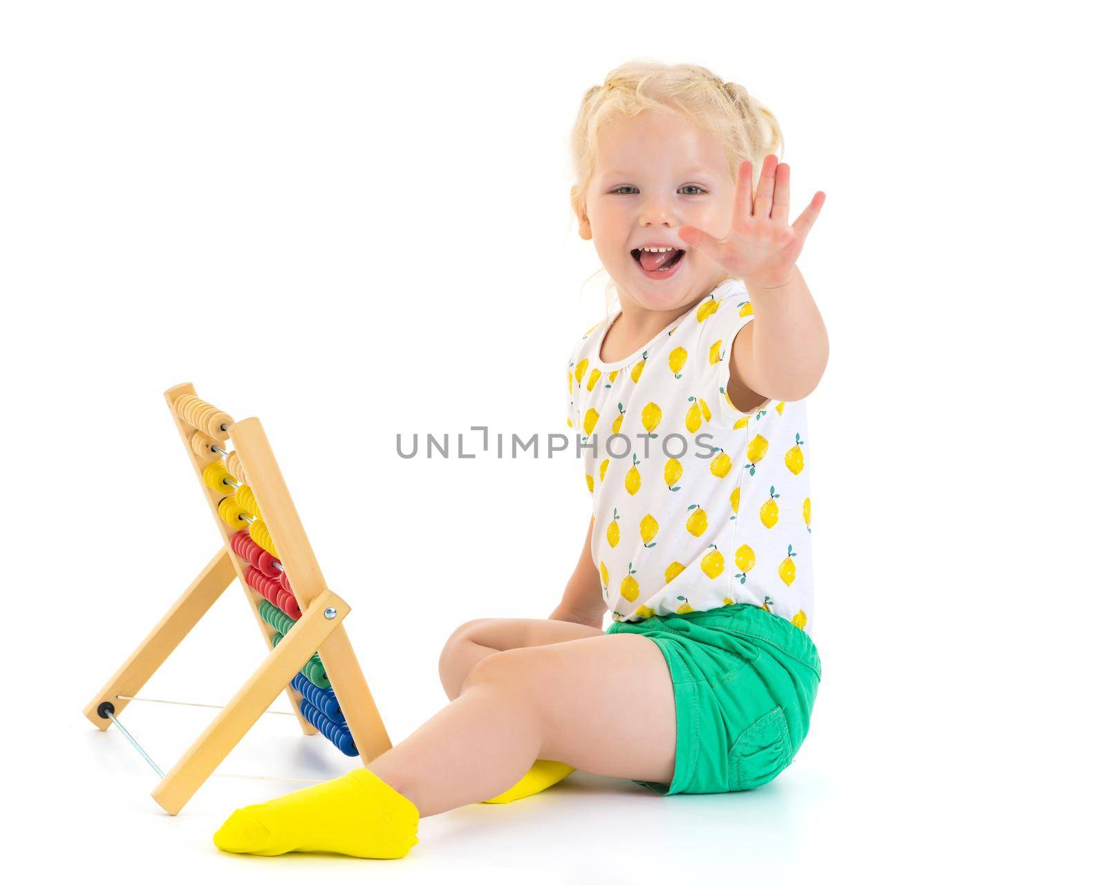 Cute little girl is playing with wooden abacus at home. An intelligent child learns to count. She enjoys with an educational toy at home or in kindergarten. Isolated on white background.
