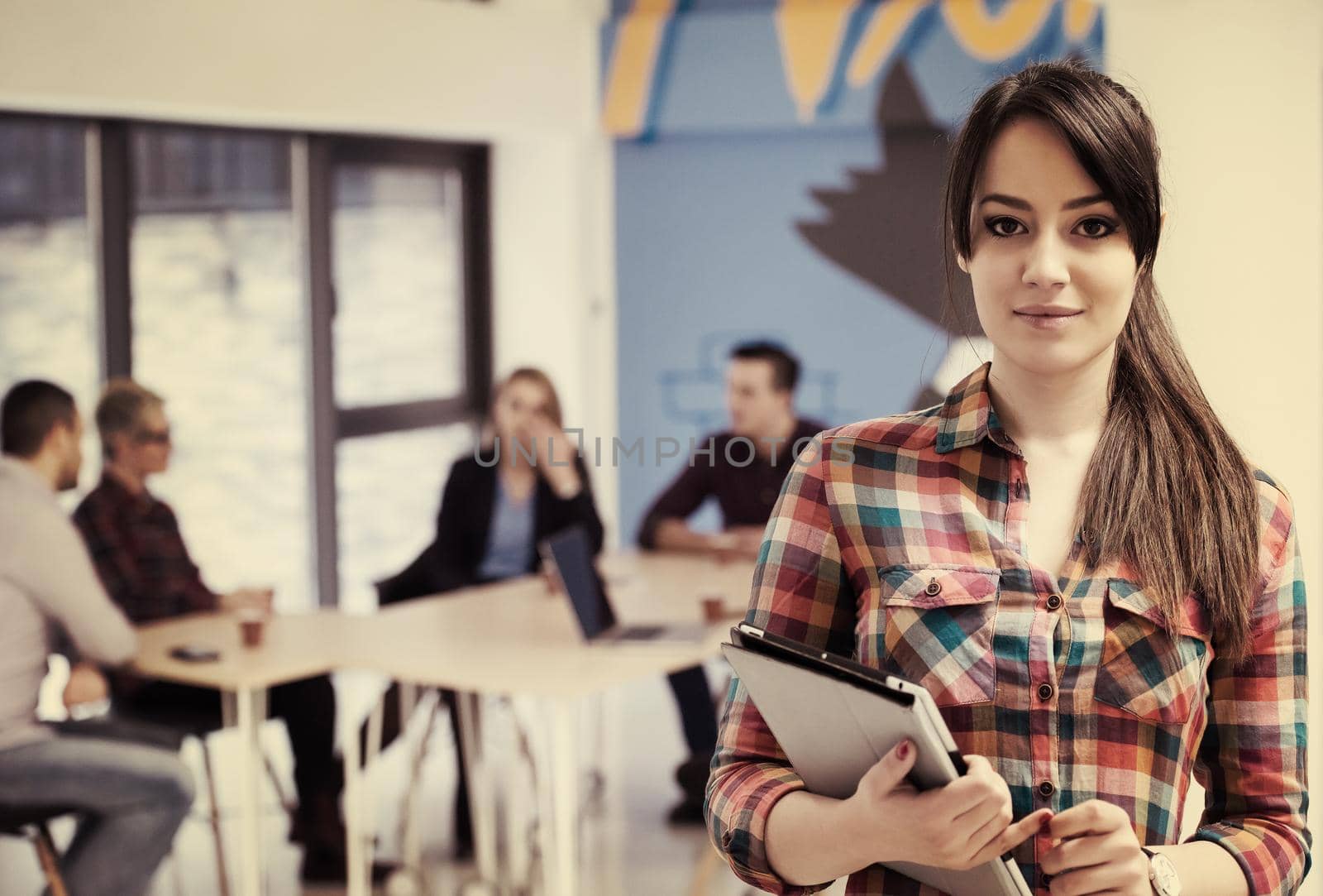 portrait of young business woman at modern startup office interior, team in meeting in background