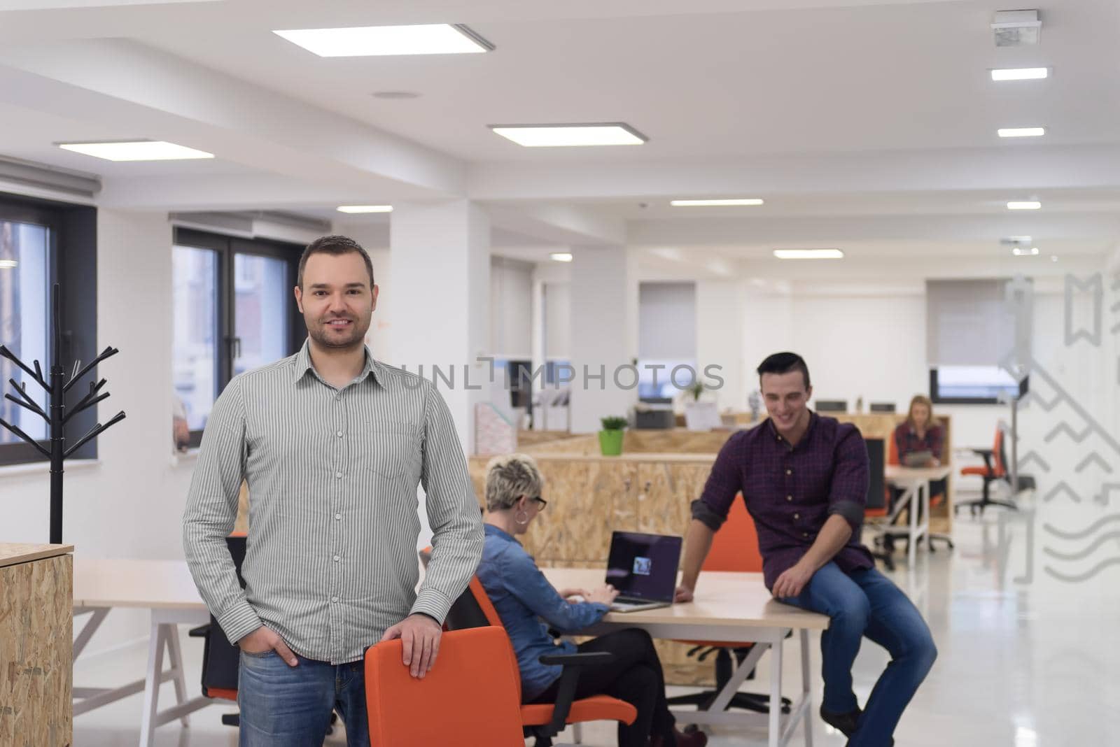 portrait of young businessman in casual clothes at modern  startup business office space,  team of people working together in background