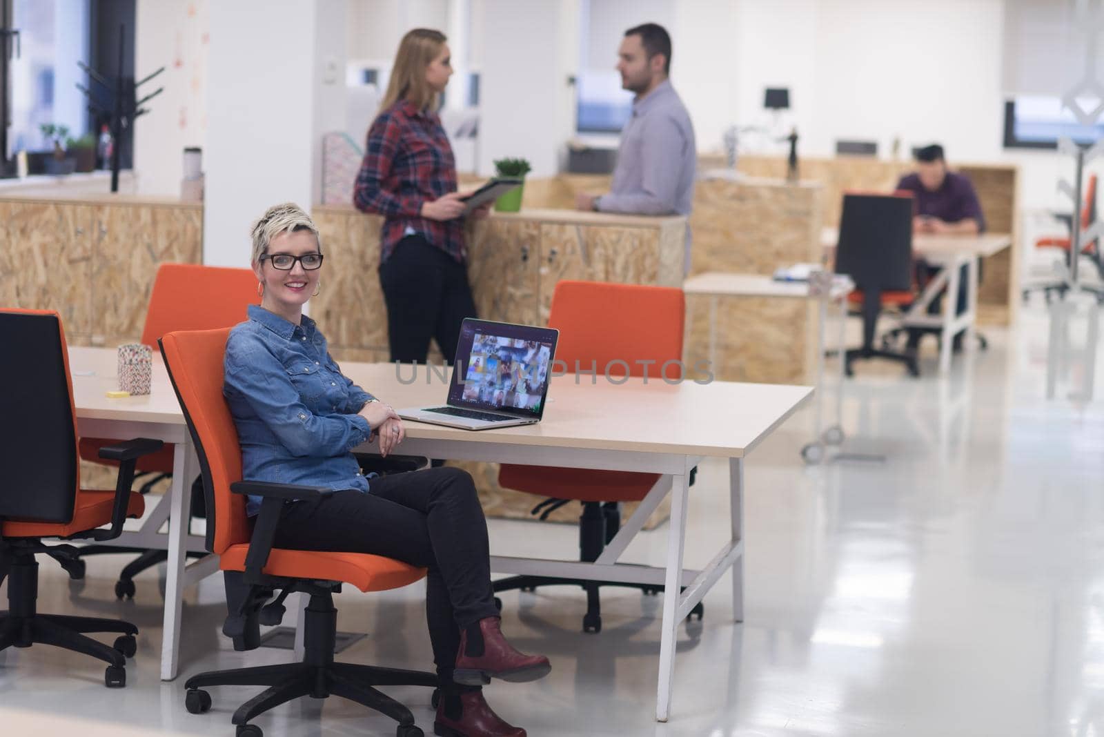 portrait of young business woman at modern startup office interior, team in meeting in background