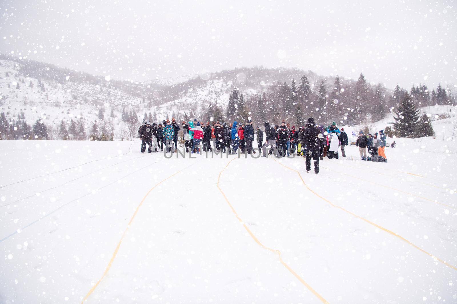 group of young happy business people having a running in bag competition while enjoying snowy winter day with snowflakes around them during a team building in the mountain forest