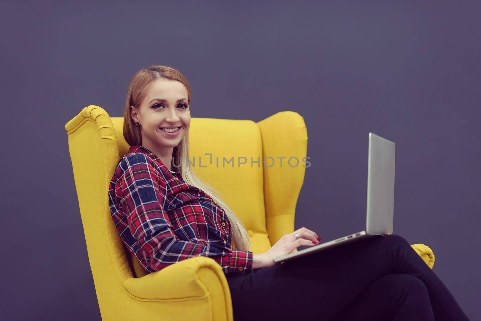 startup business, woman  working on laptop and sitting on yellow armchair by dotshock