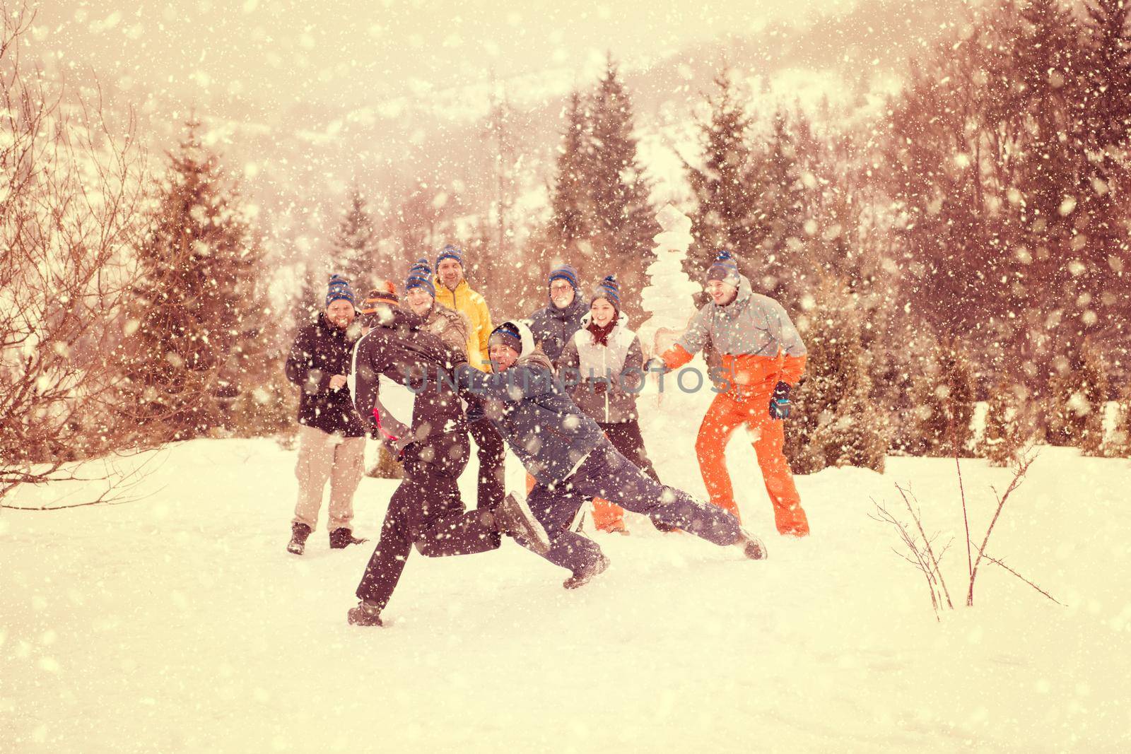 group of young happy business people having fun while enjoying snowy winter day with snowflakes around them during a team building in the mountain forest