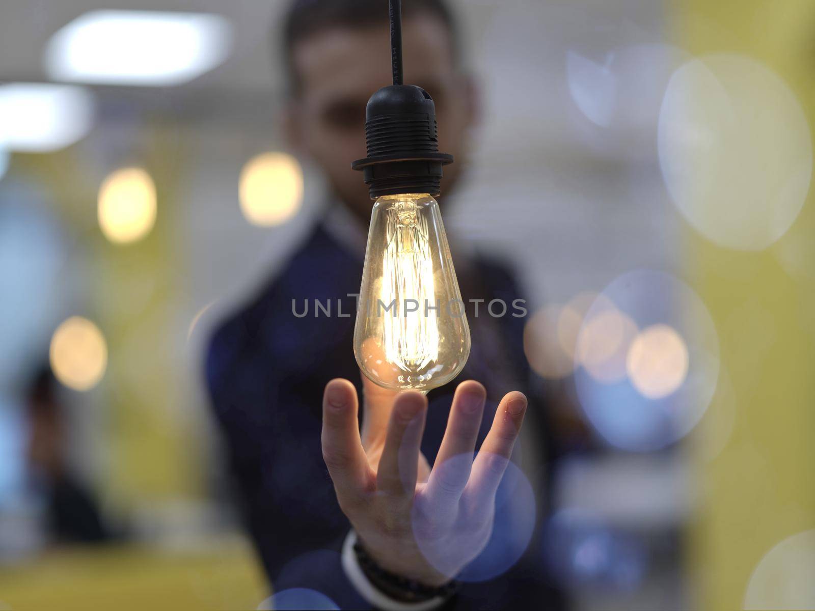 businessman holding hand around light bulb by dotshock