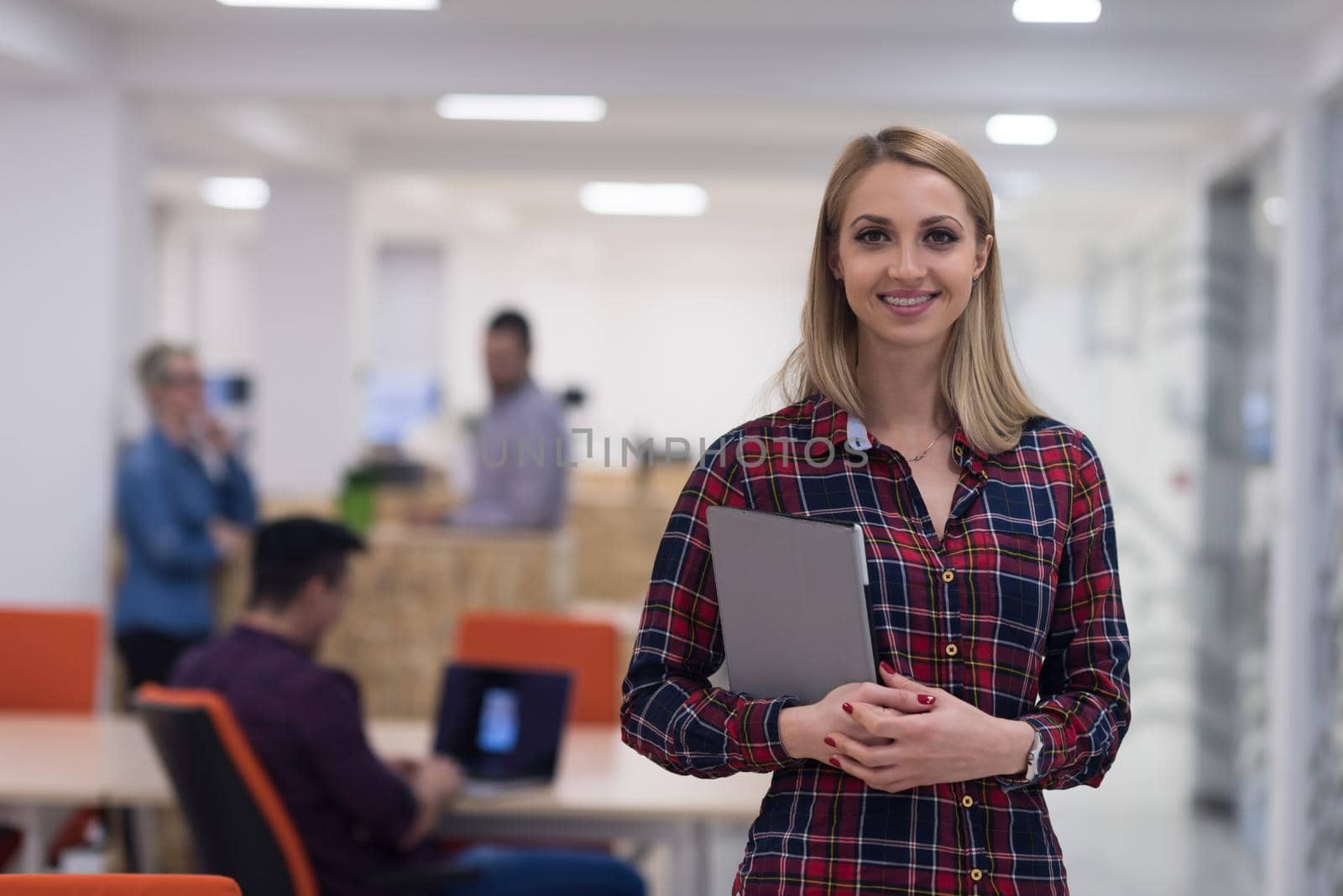 portrait of young business woman at office with team in background by dotshock