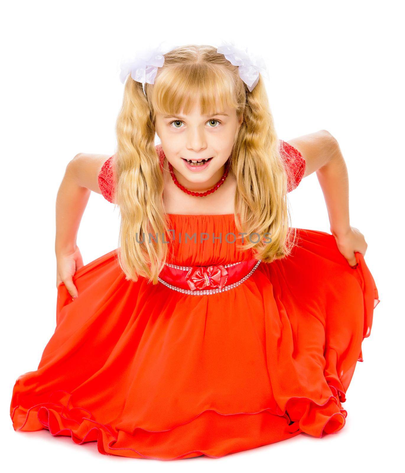 A beautiful little Caucasian girl with long, blonde ponytails on her head in a bright orange dress . Sat down on the floor-Isolated on white background